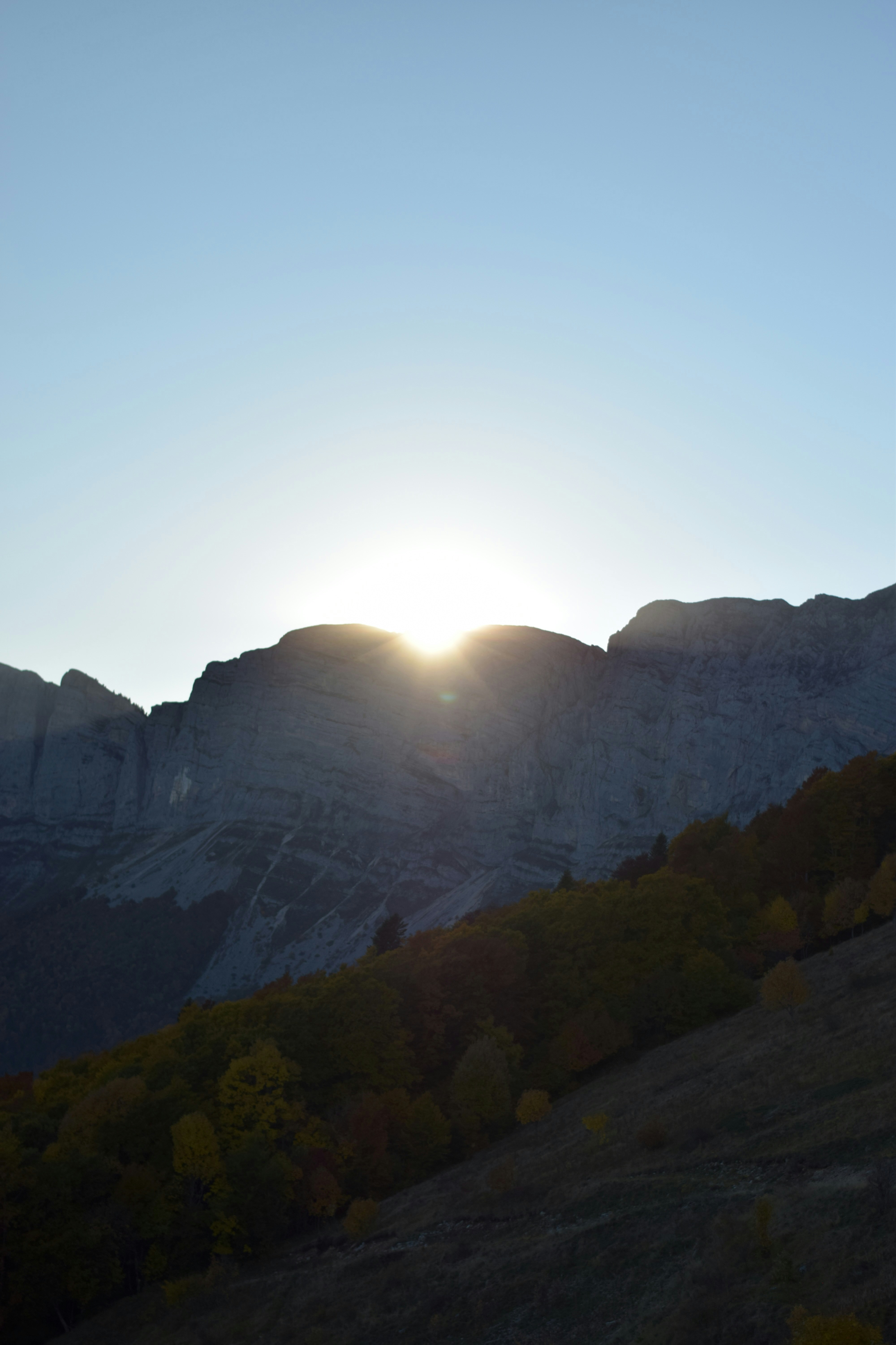 해질녘에 바위산봉우리 뒤로 지는 해.