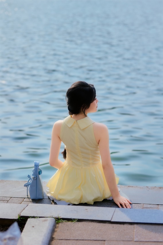 Woman in yellow dress sitting by the water