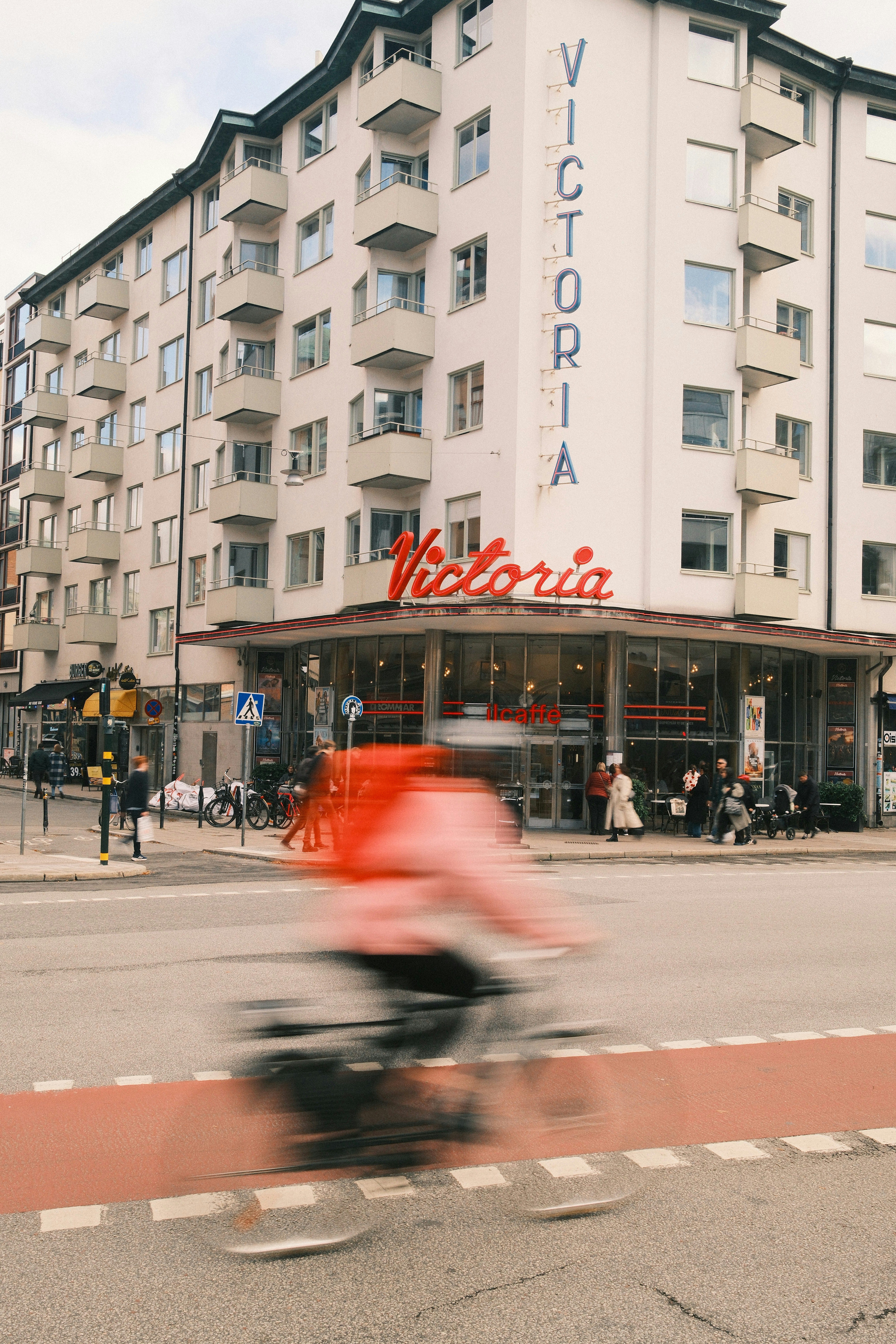 A cyclist rides past a building with a "victoria" sign.
