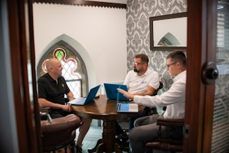 Three men in a meeting with laptops.