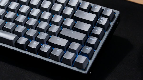 Close-up of a gray mechanical keyboard with blue backlighting.