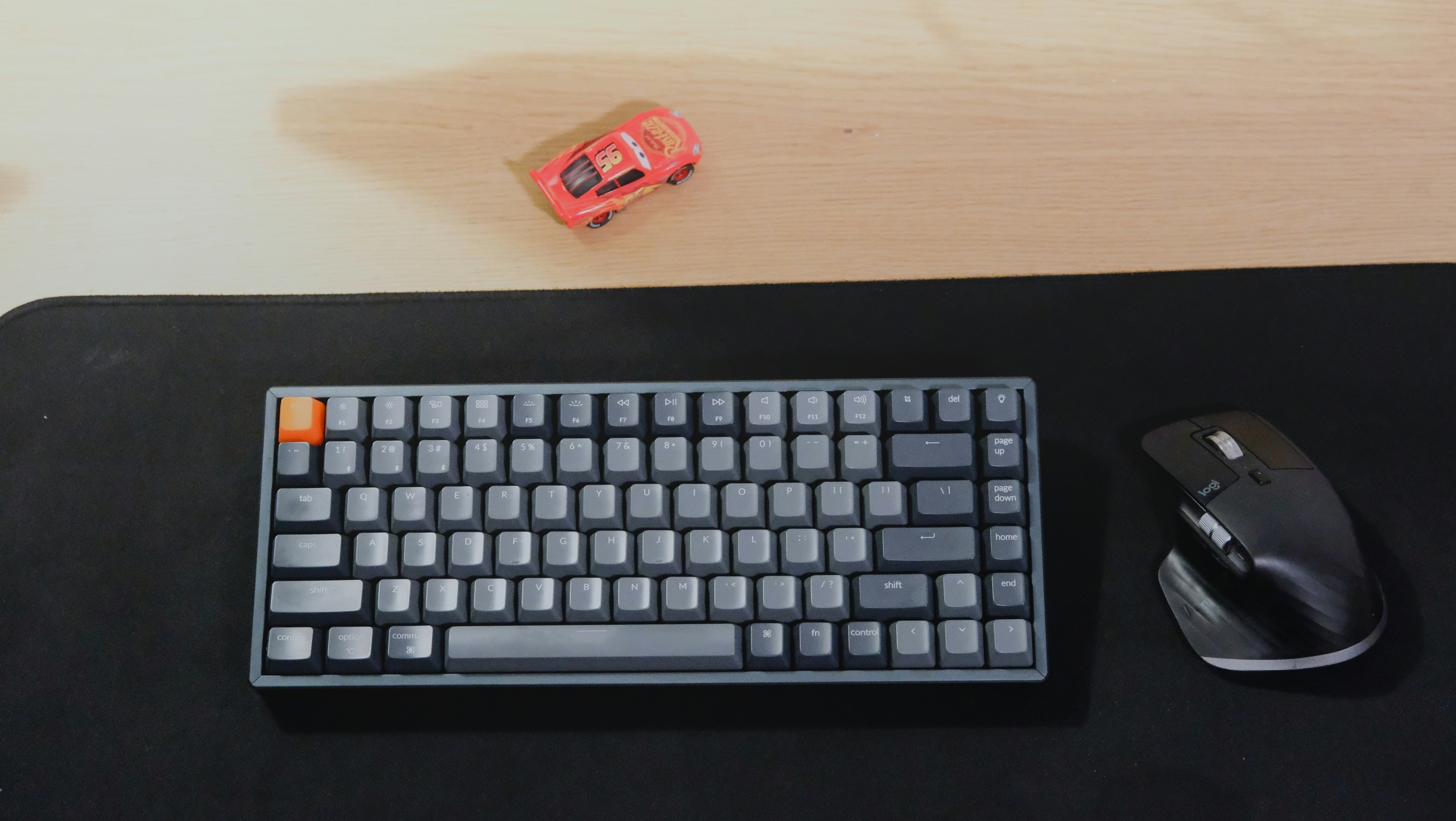 A small toy car rests above a keyboard and mouse.