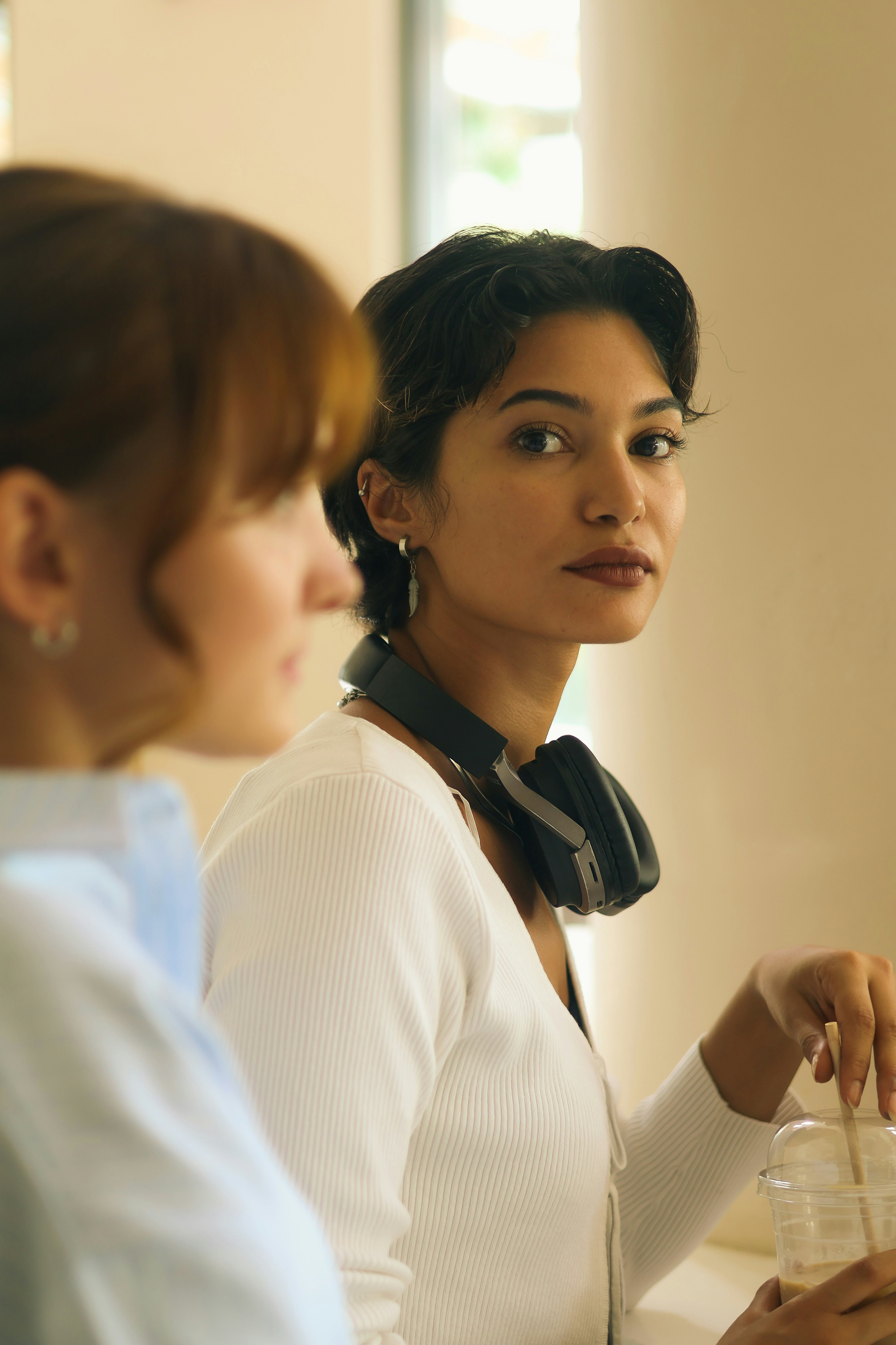 Zwei Frauen sitzen drinnen an einem Tisch.