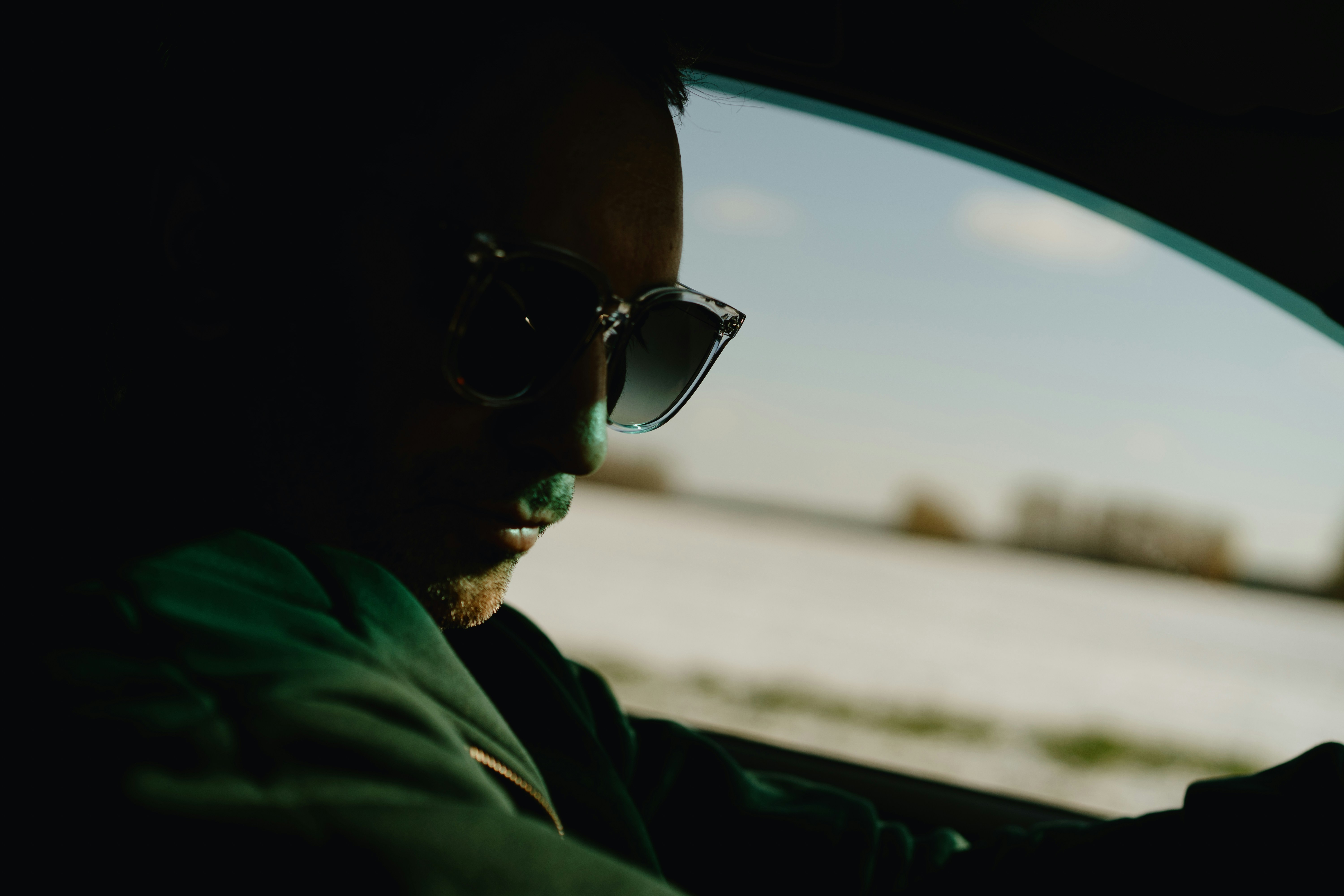 Uomo che indossa occhiali da sole alla guida di un'auto