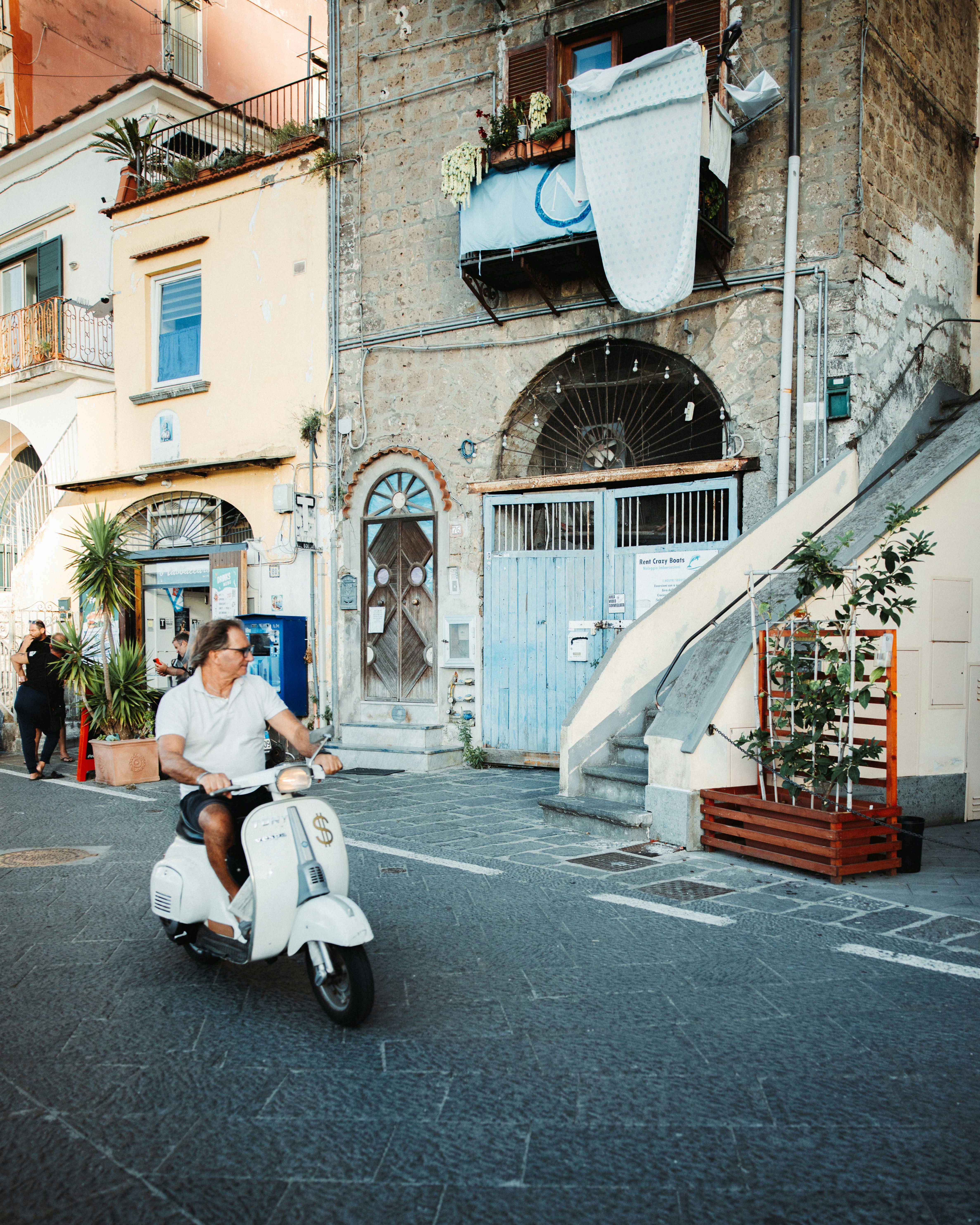 Man riding a white scooter down a street.