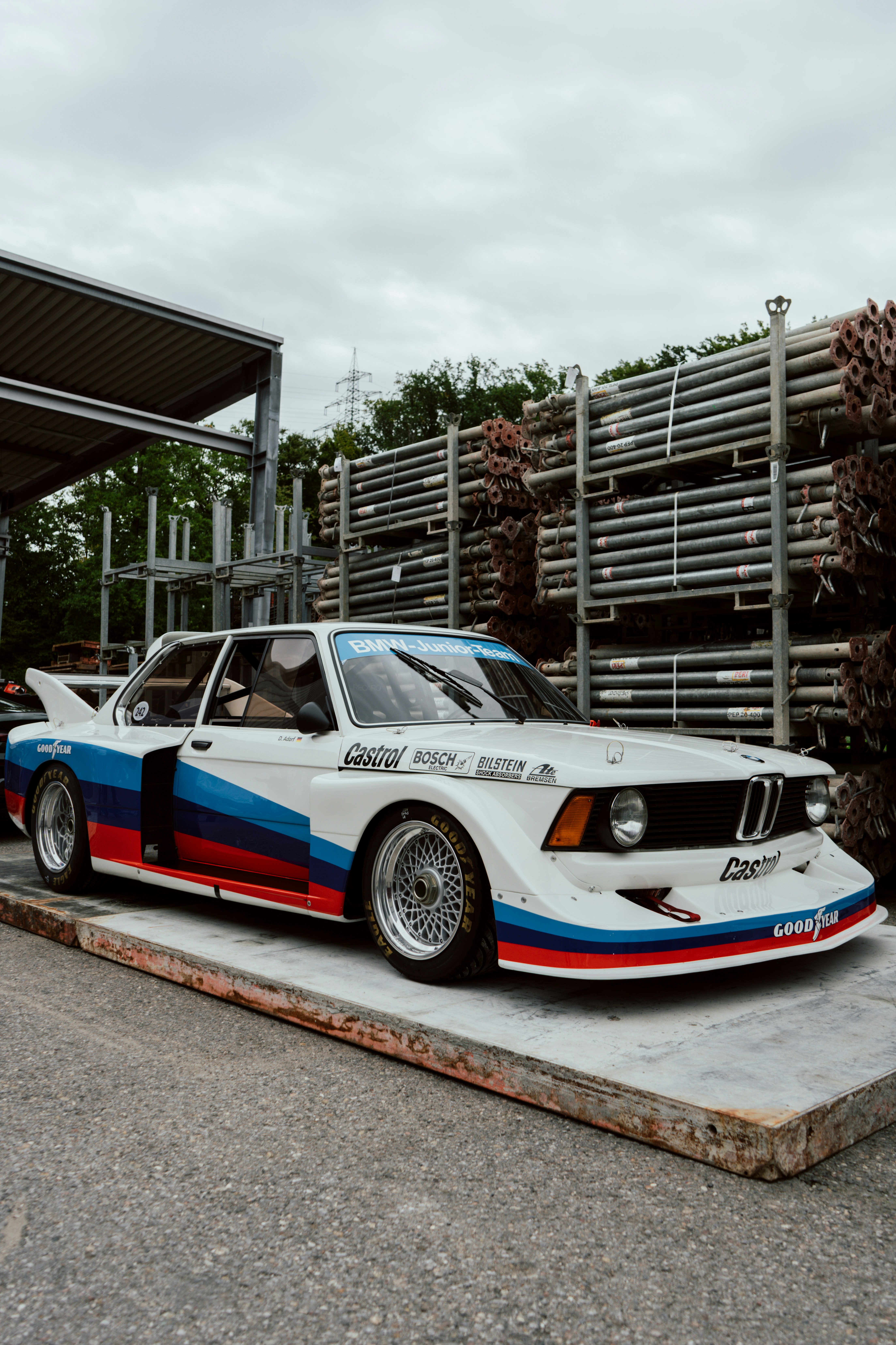 Auto da corsa BMW d'epoca con livrea da corsa parcheggiata all'aperto.