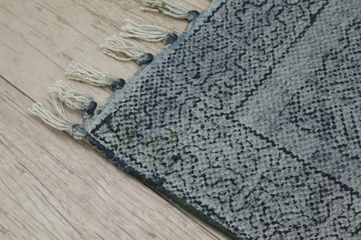 Close-up of a blue patterned rug with tassels.