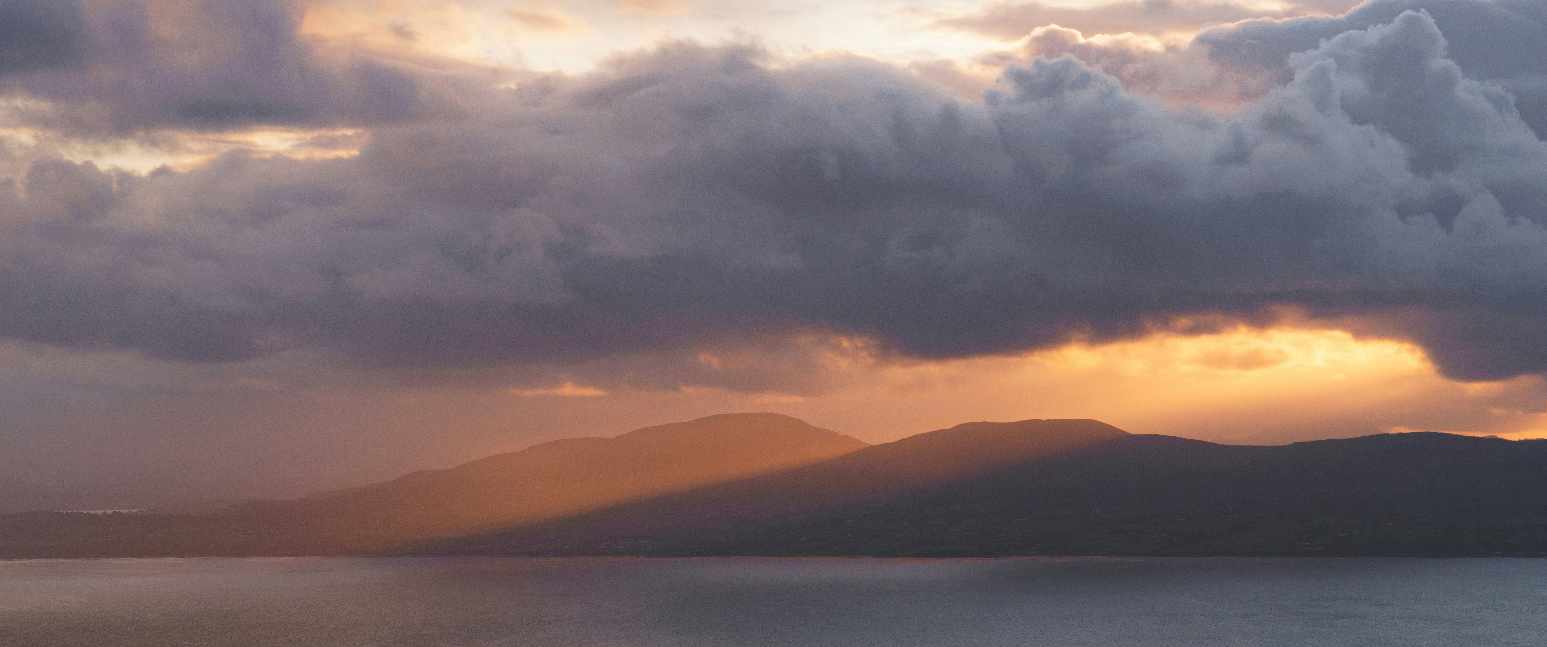 Dramatic sunset over mountains and calm water