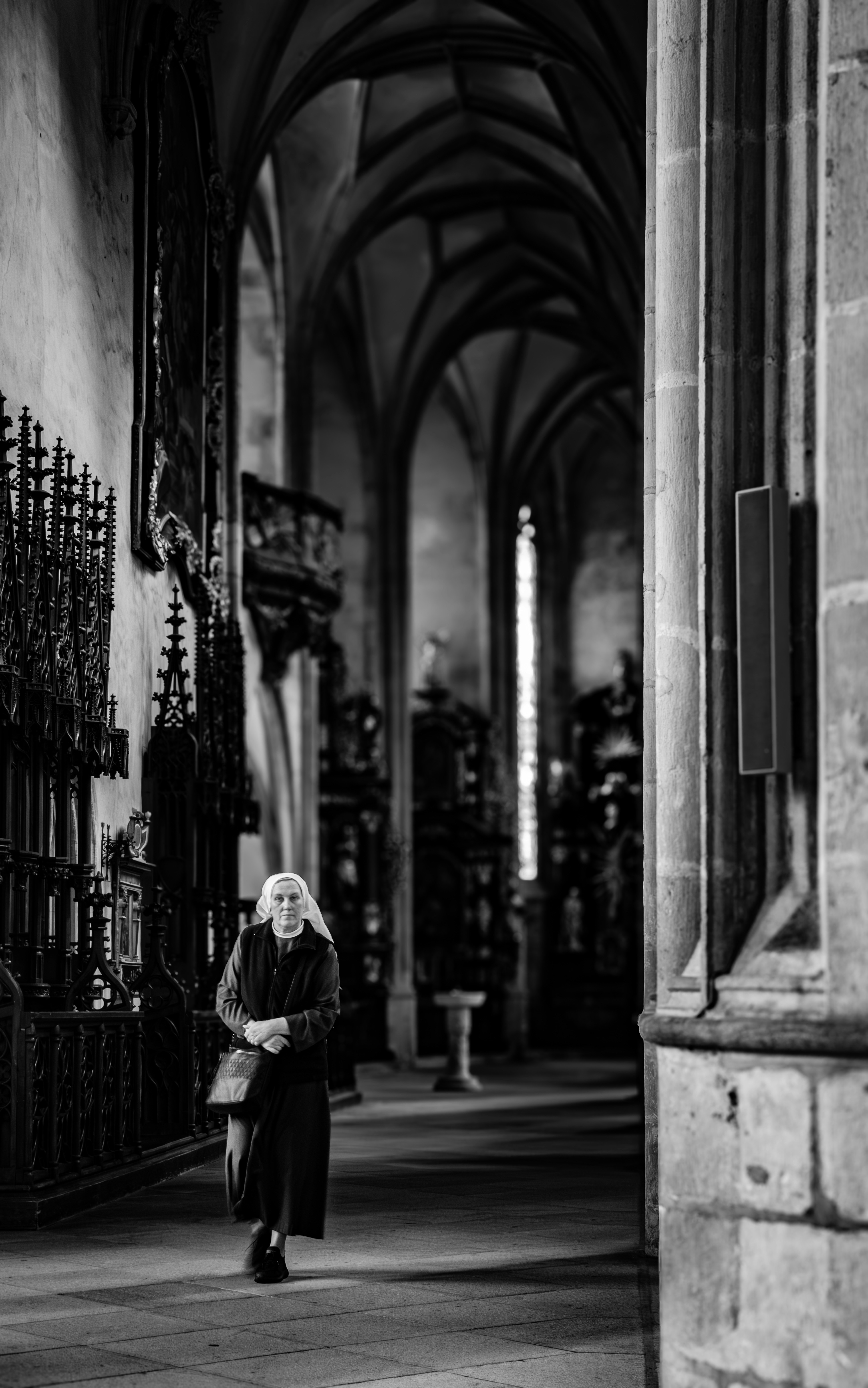 Elderly woman walking through a grand cathedral hall.