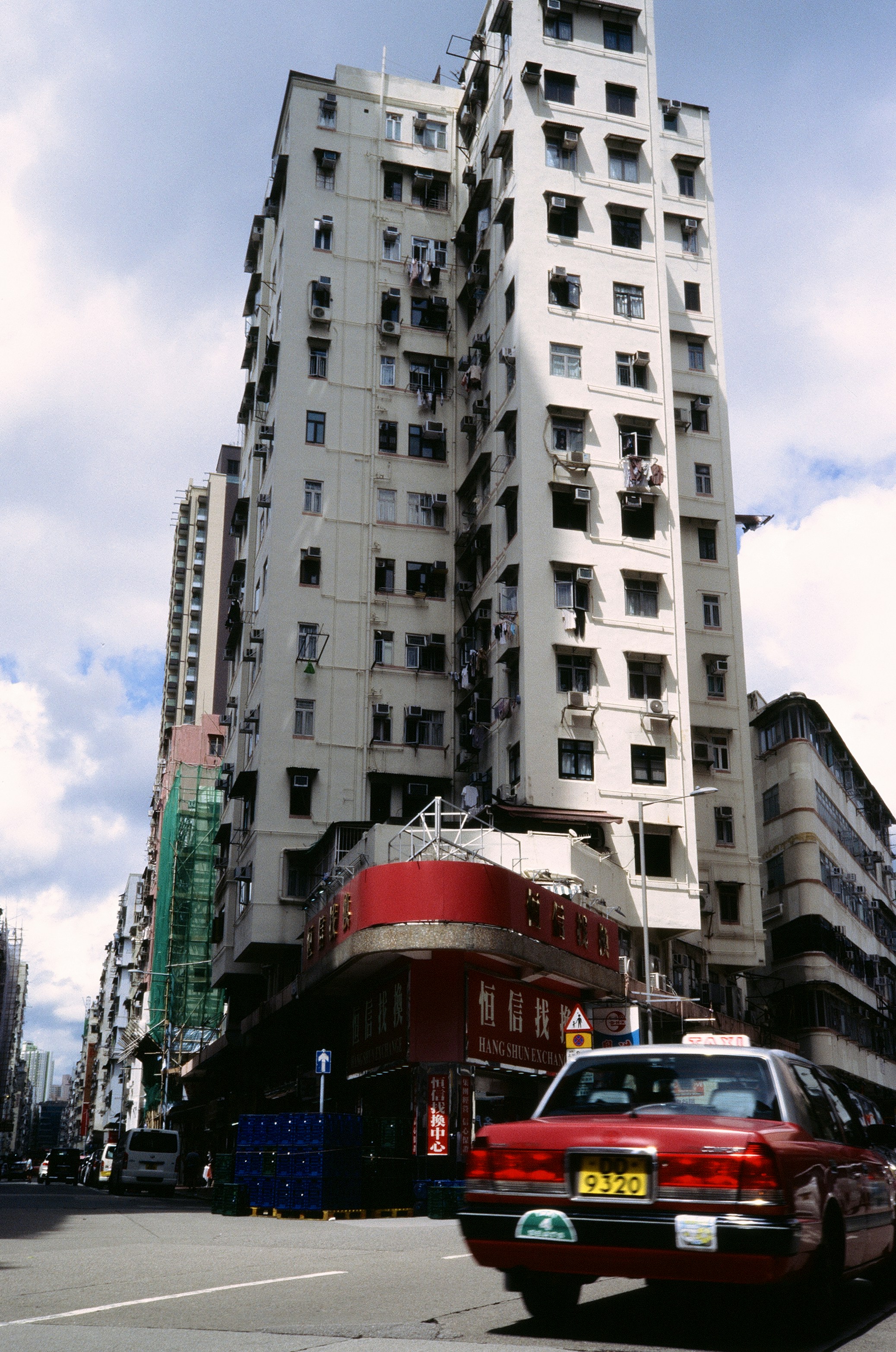 Tall apartment buildings line a city street with taxi.