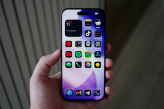 Hand holding a smartphone with colorful apps displayed.