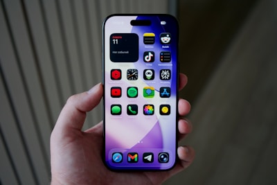 Hand holding a smartphone with colorful apps displayed.