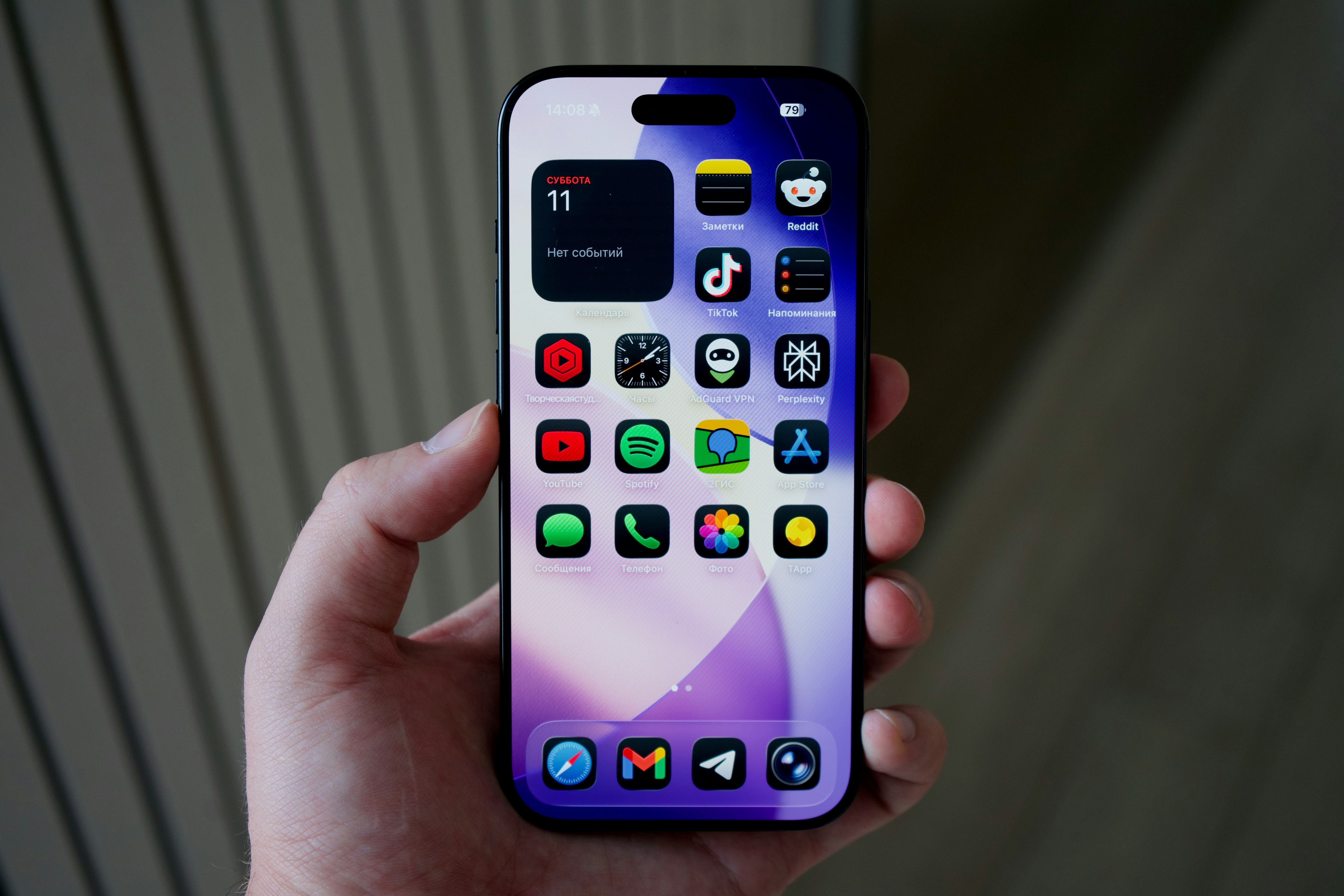 Hand holding a smartphone with colorful apps displayed.