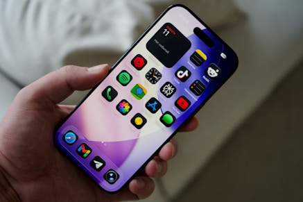 Hand holding a smartphone with colorful app icons.