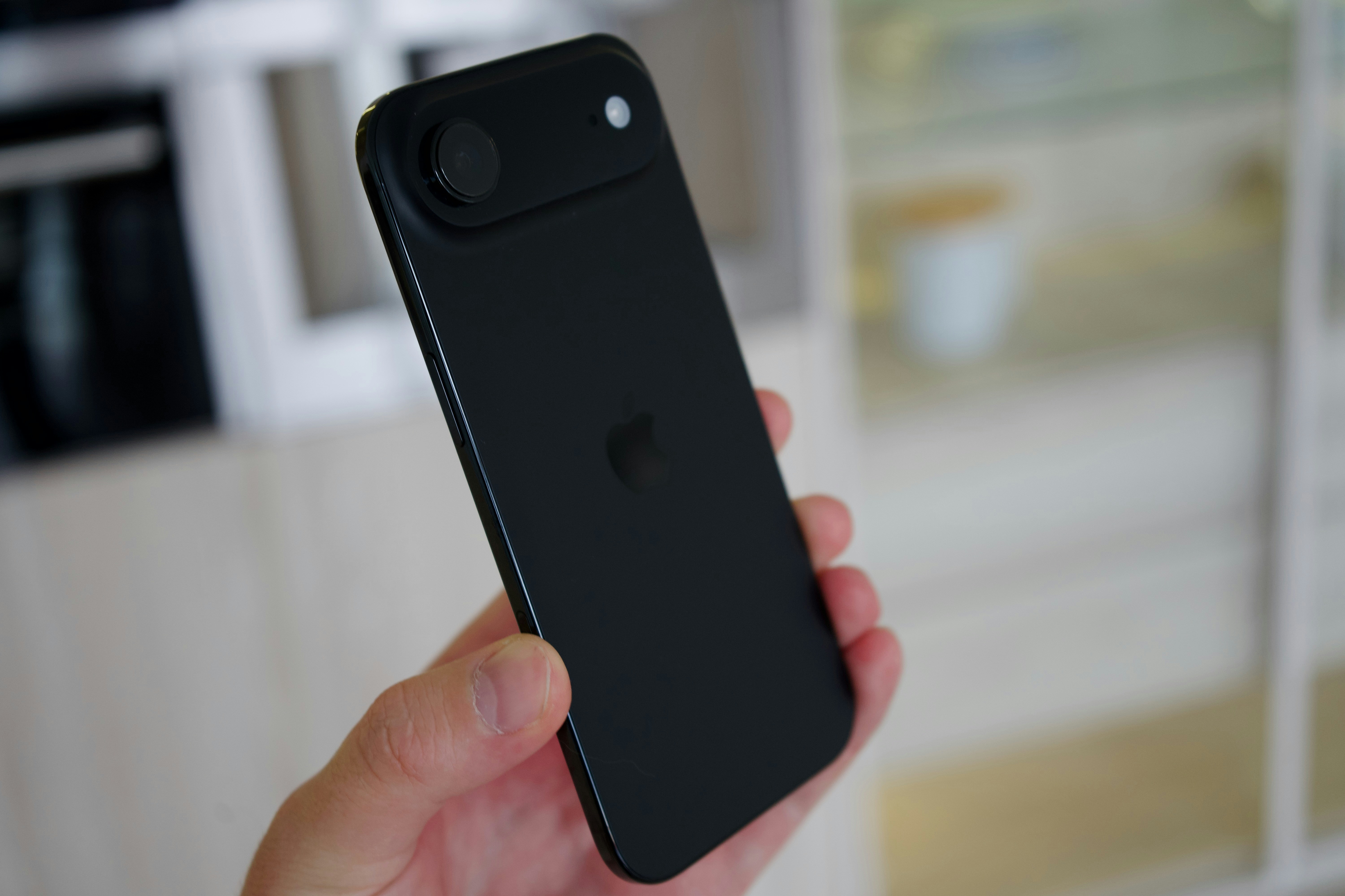 Una mano sostiene un teléfono inteligente negro con una lente de cámara.