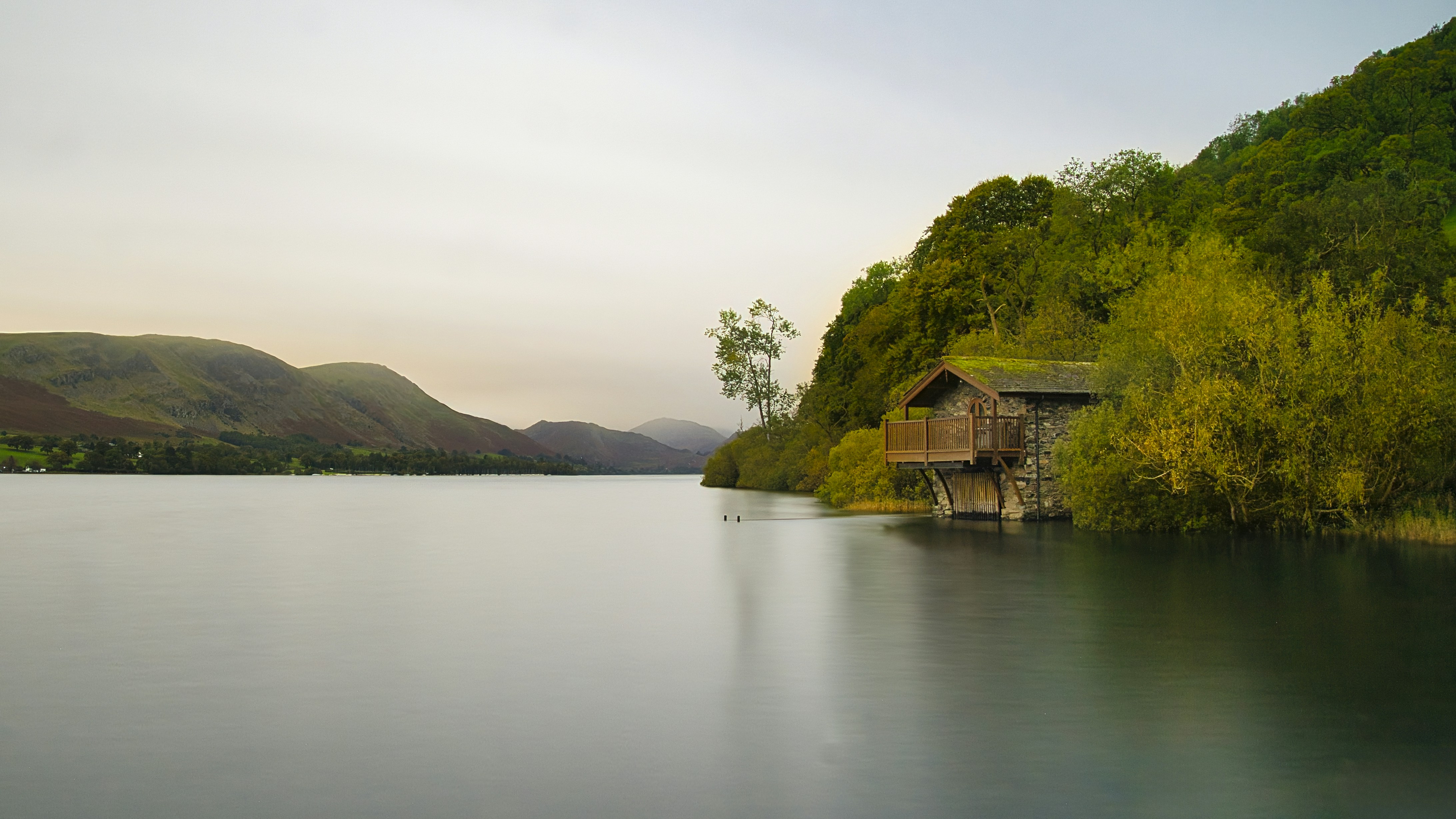 Calm lake beside a wooded hillside with boathouse
