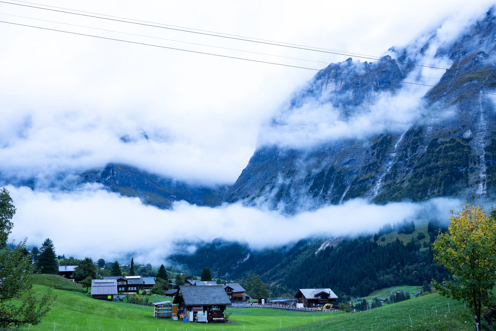 Traditional Swiss Alpine village with wooden chalets nestled among snow-capped mountain peaks and green meadows