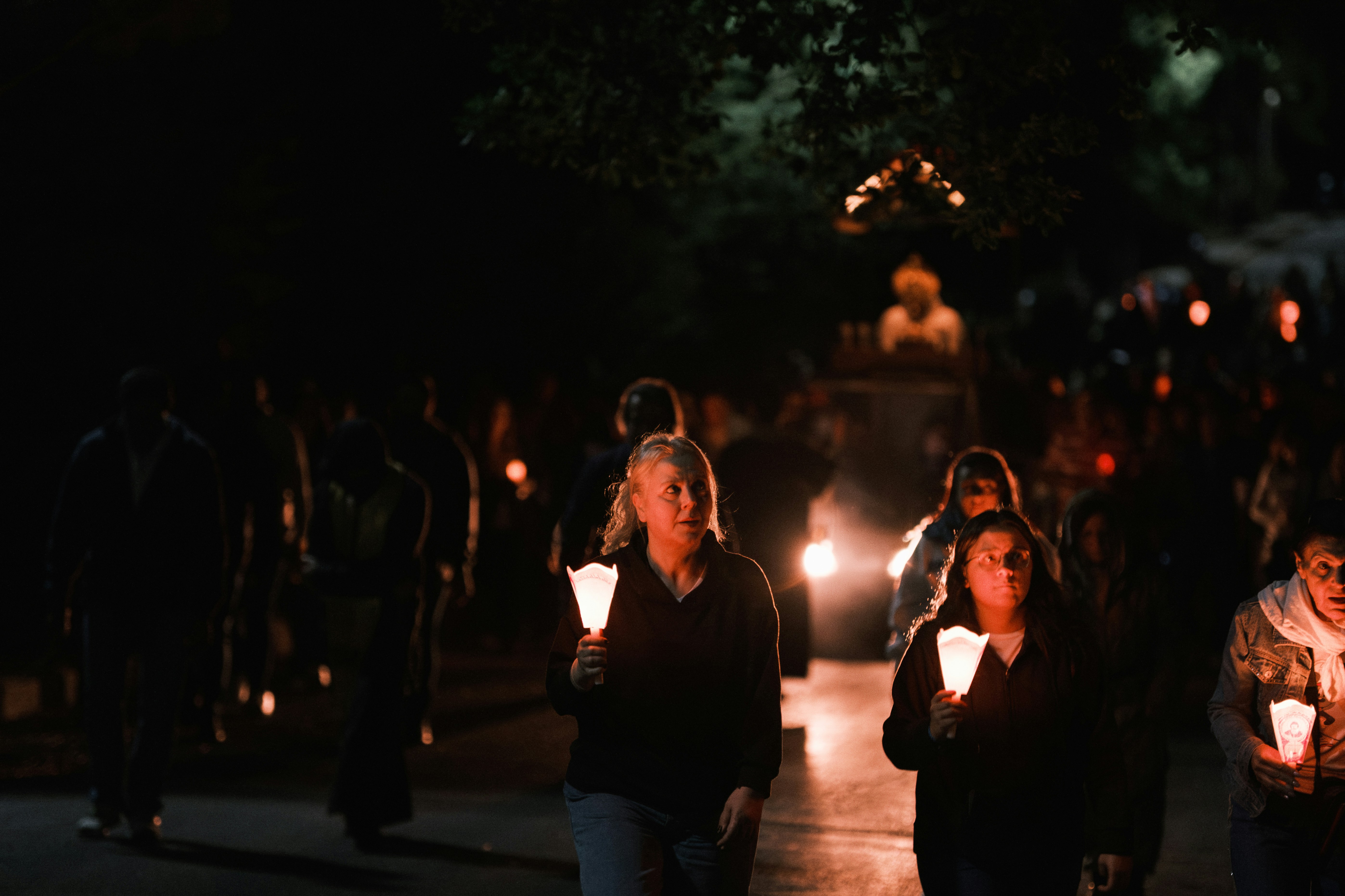 People holding candles walking at night