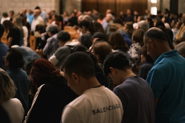 A crowd of people bowing their heads in prayer.