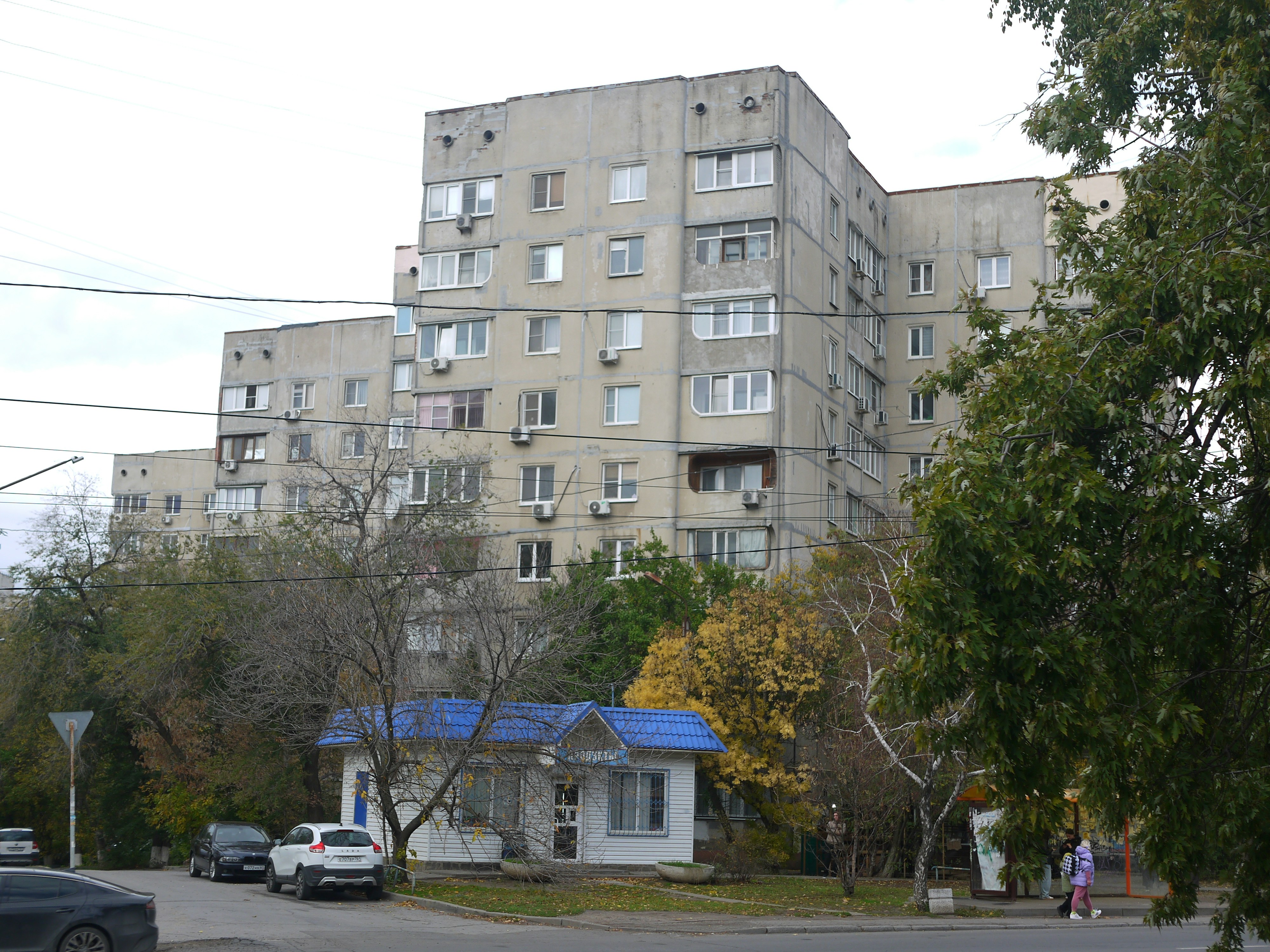 Ein Mehrfamilienhaus aus Beton mit Bäumen davor.