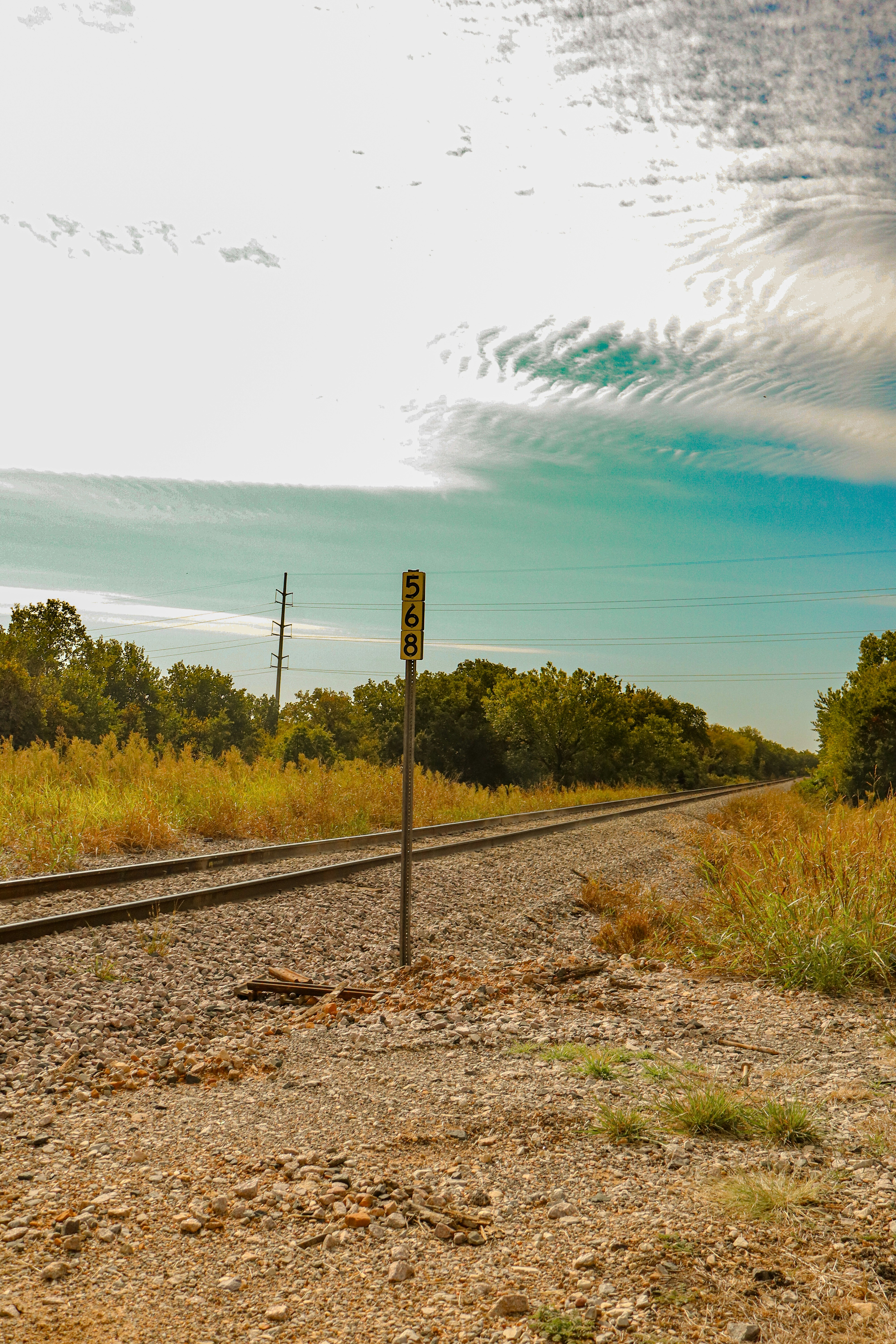 Railroad tracks stretch into the distance under a cloudy sky.