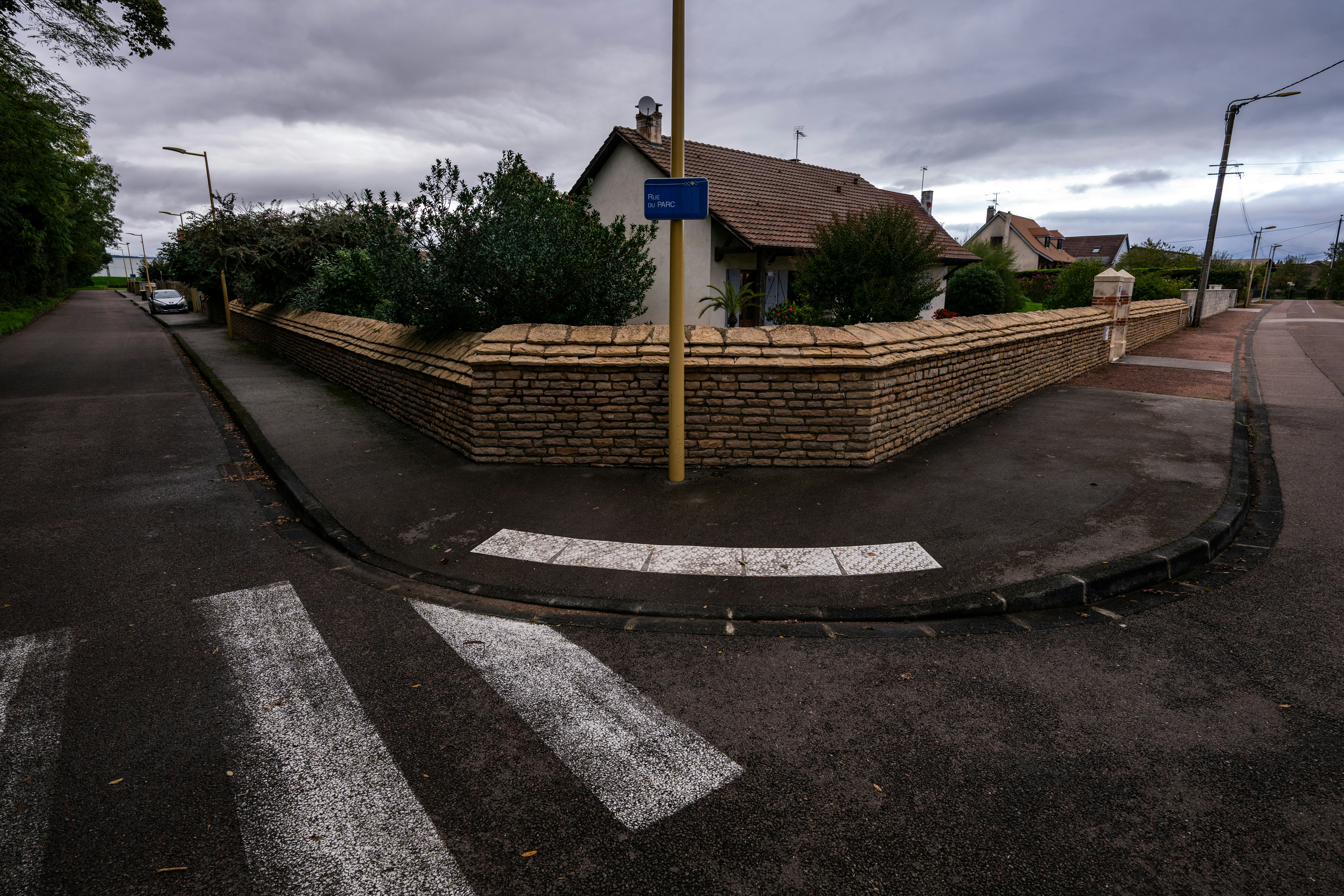 A quiet street corner with a house and crosswalk.