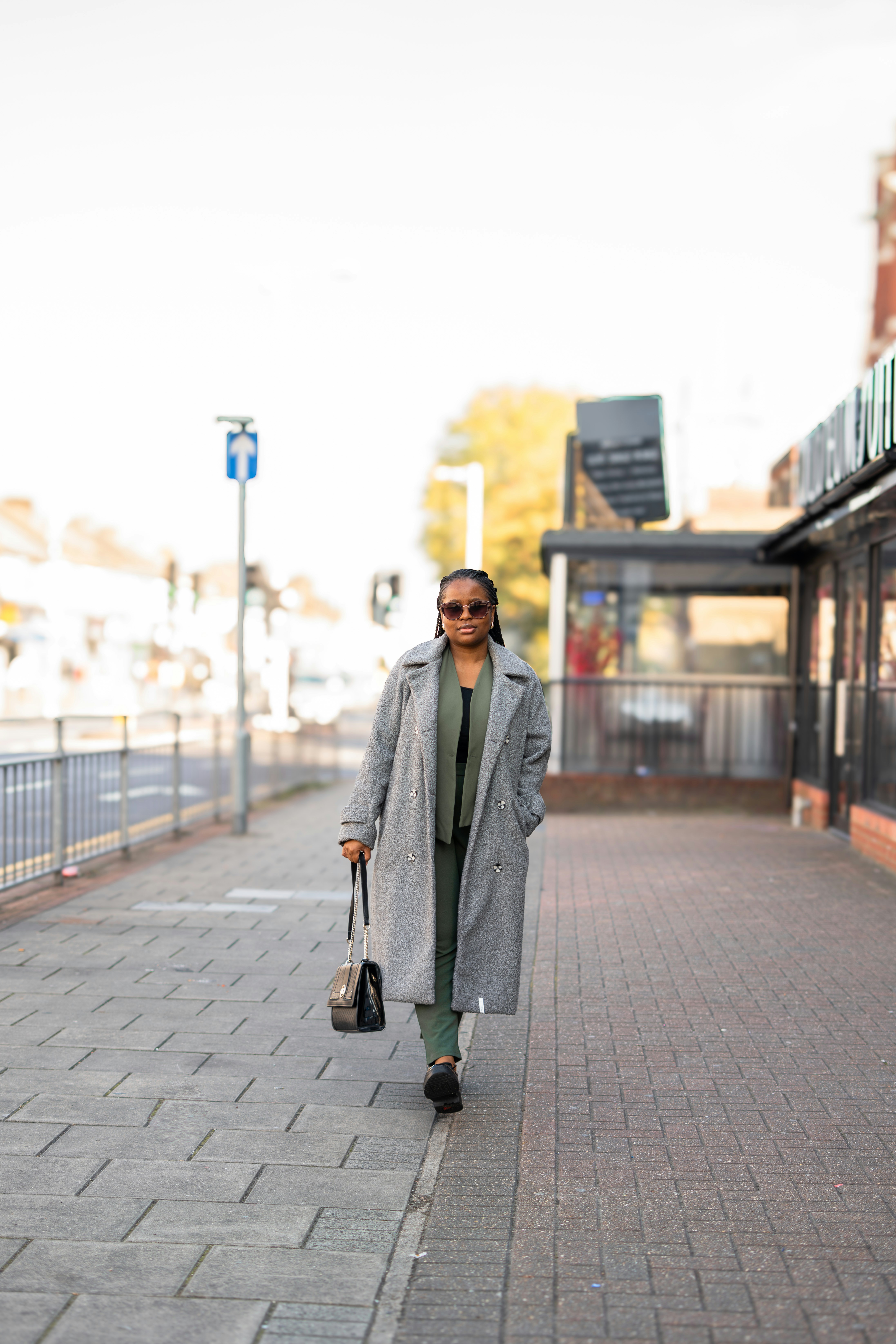 Woman walking on sidewalk with a handbag.
