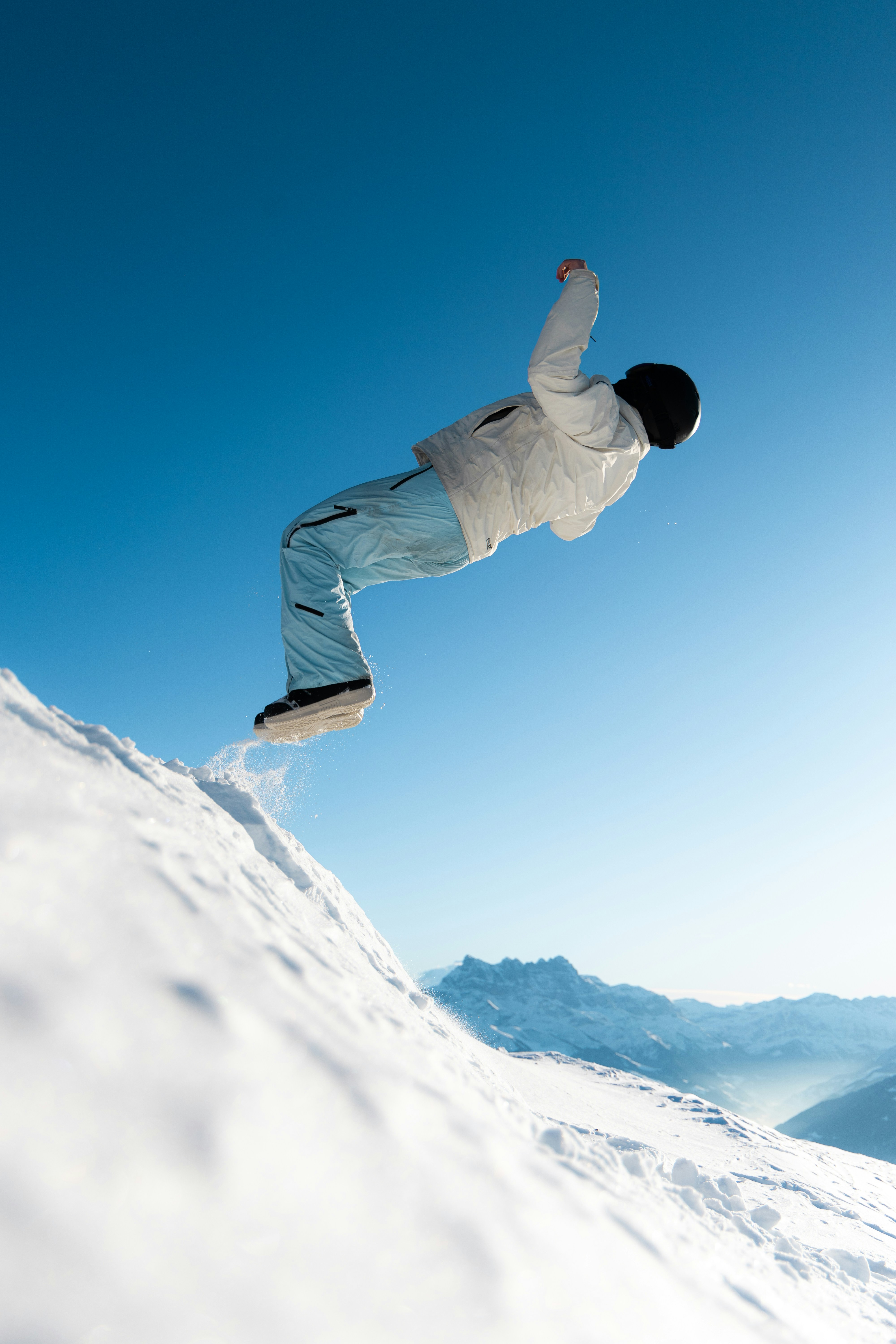 Snowboarder performs a jump on a snowy mountain.