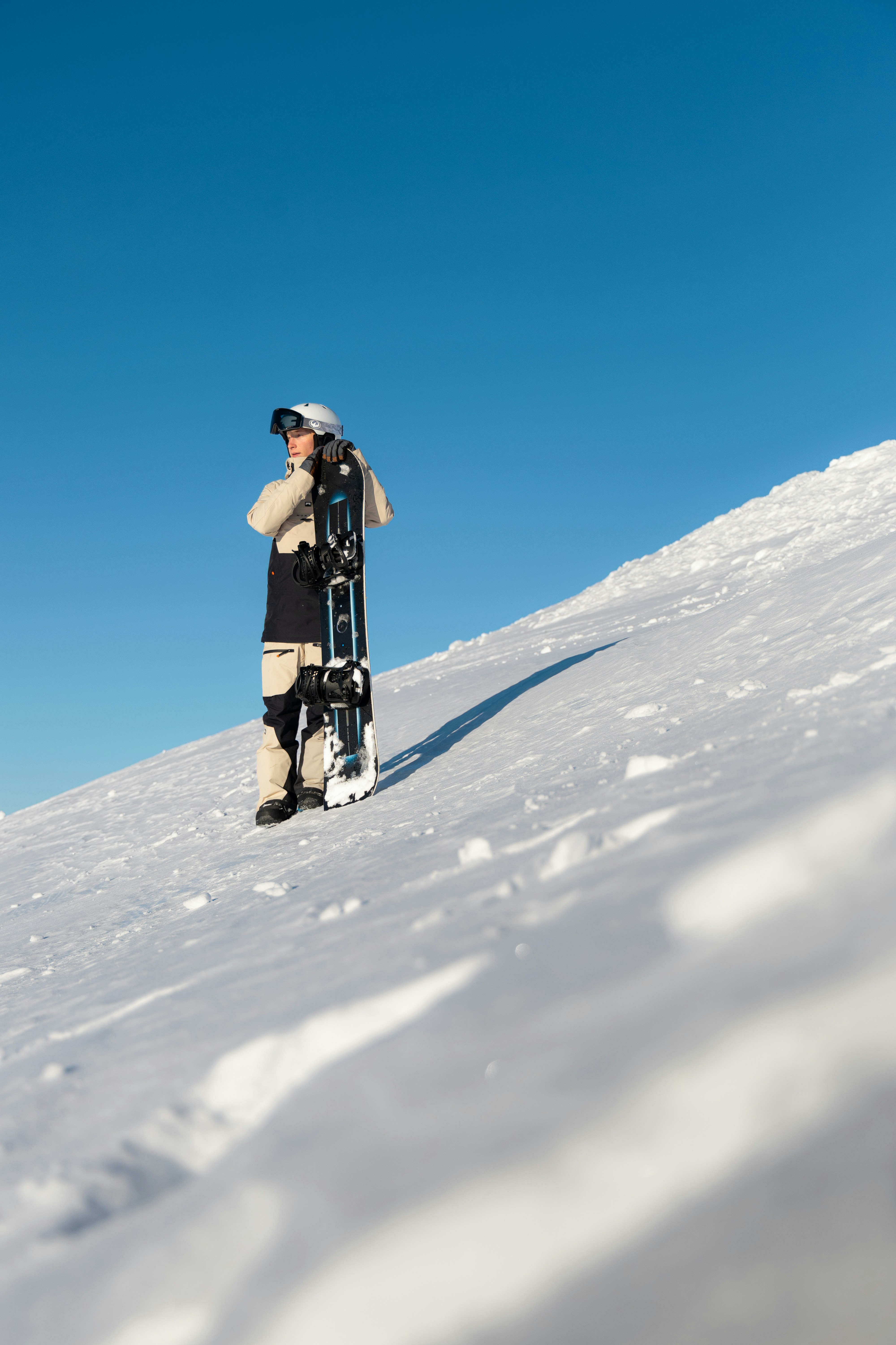 Snowboarder standing on a snowy slope under blue sky