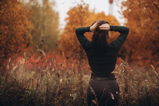 Woman with hands in hair in autumn foliage