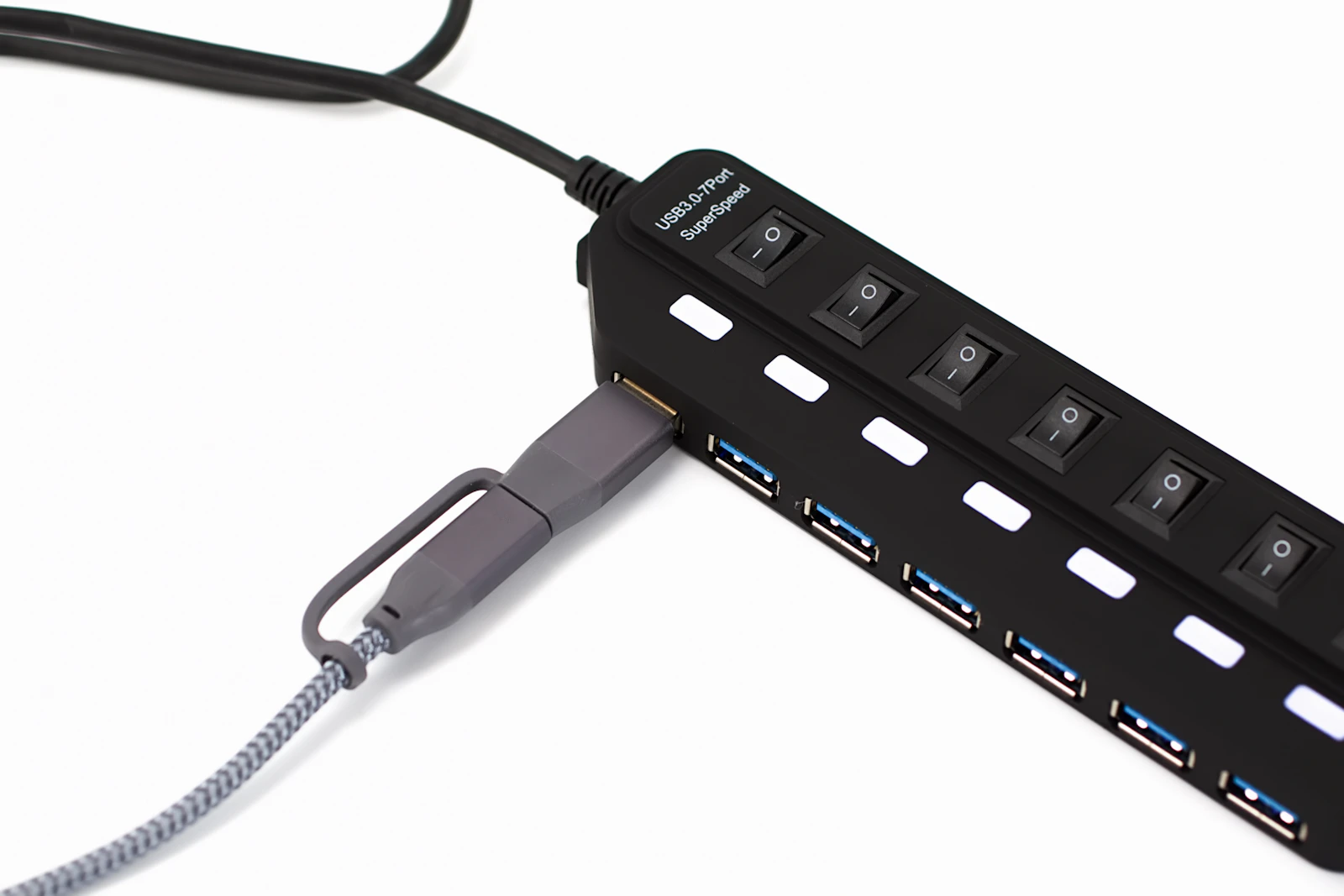 Black USB hub with multiple ports and switches on a desk, travel multiport adapter for a laptop