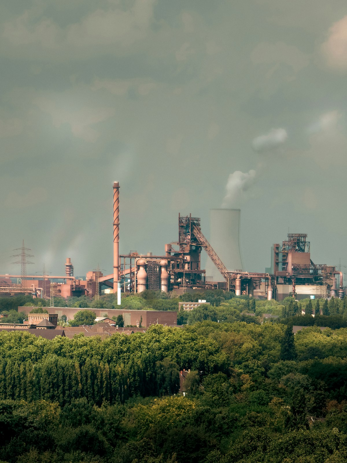 Industrial factory with smokestacks and cooling tower against a cloudy sky