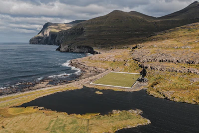Green field by the ocean with rocky cliffs