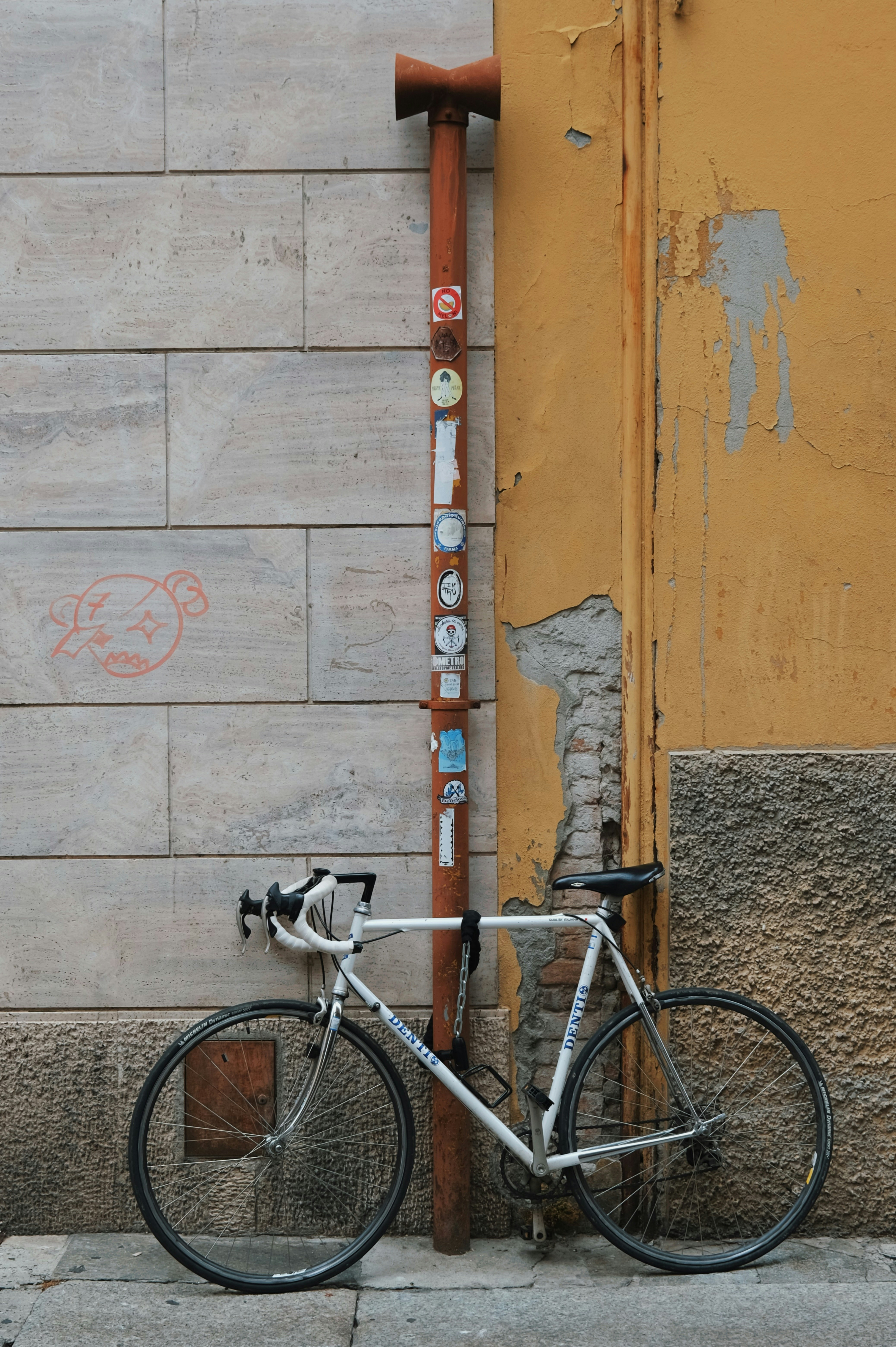 White bicycle leaning against a pole on a street