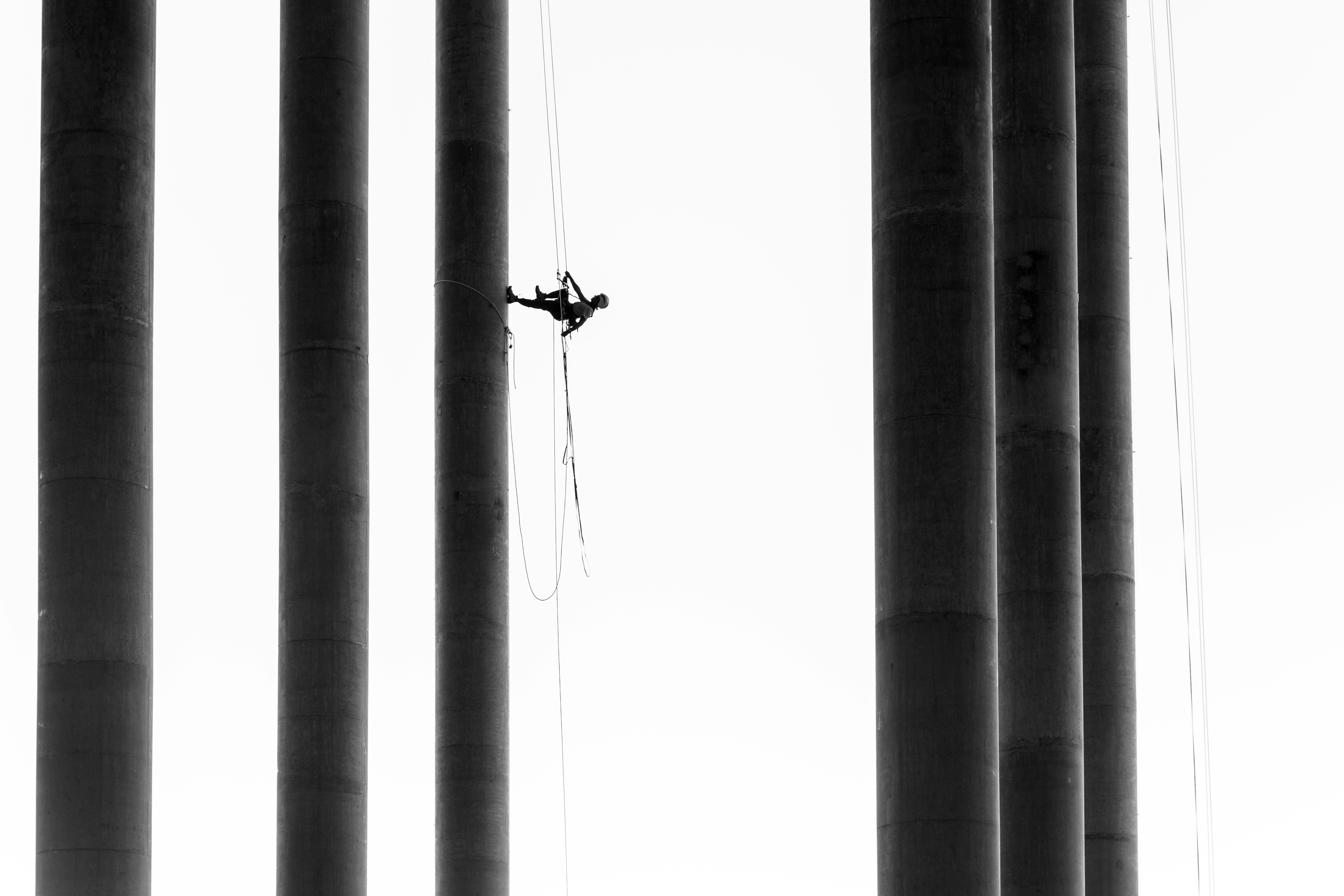 Worker rappels down tall concrete pillars