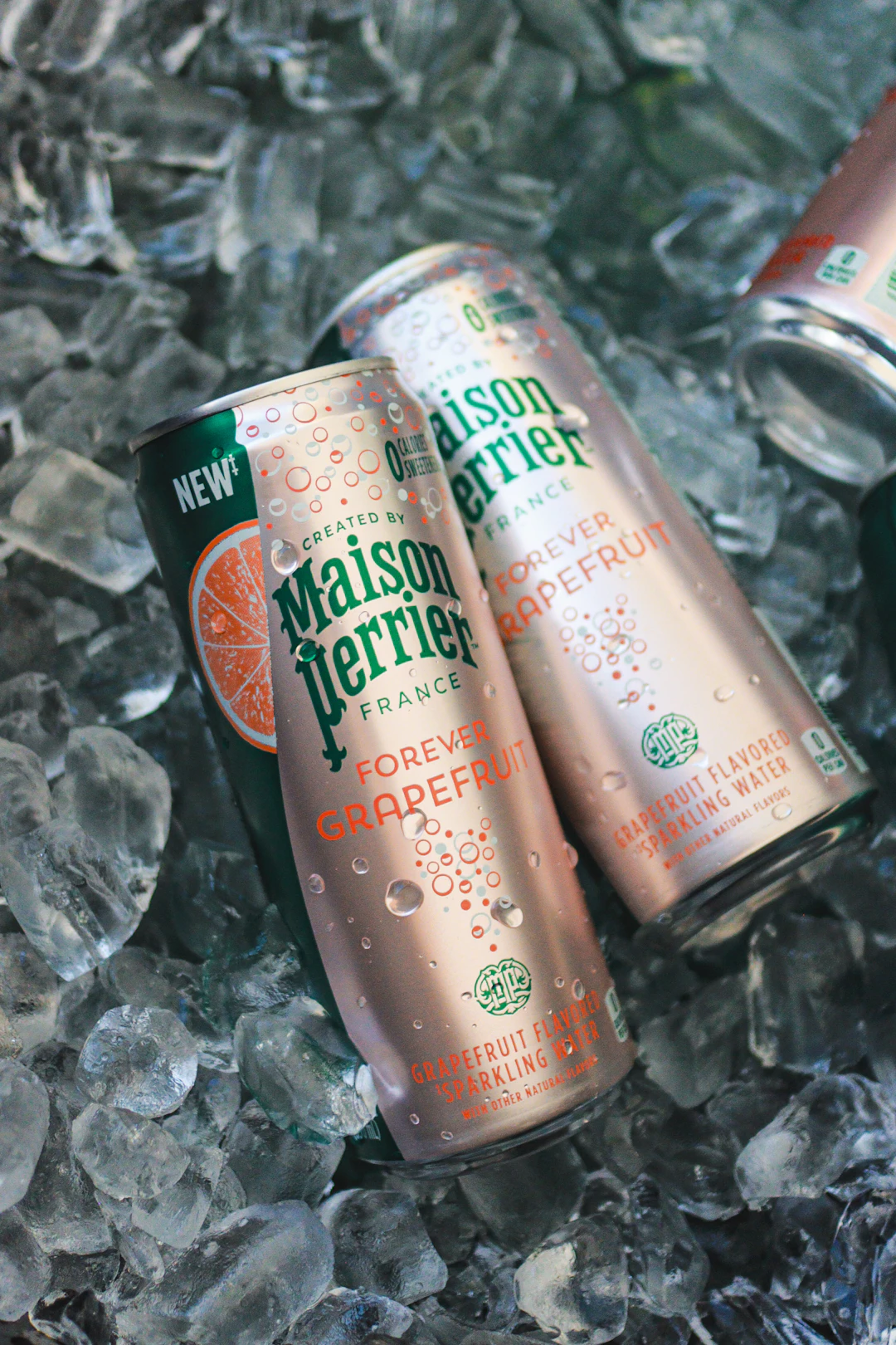 Two cans of Maison Perrier grapefruit sparkling water on ice