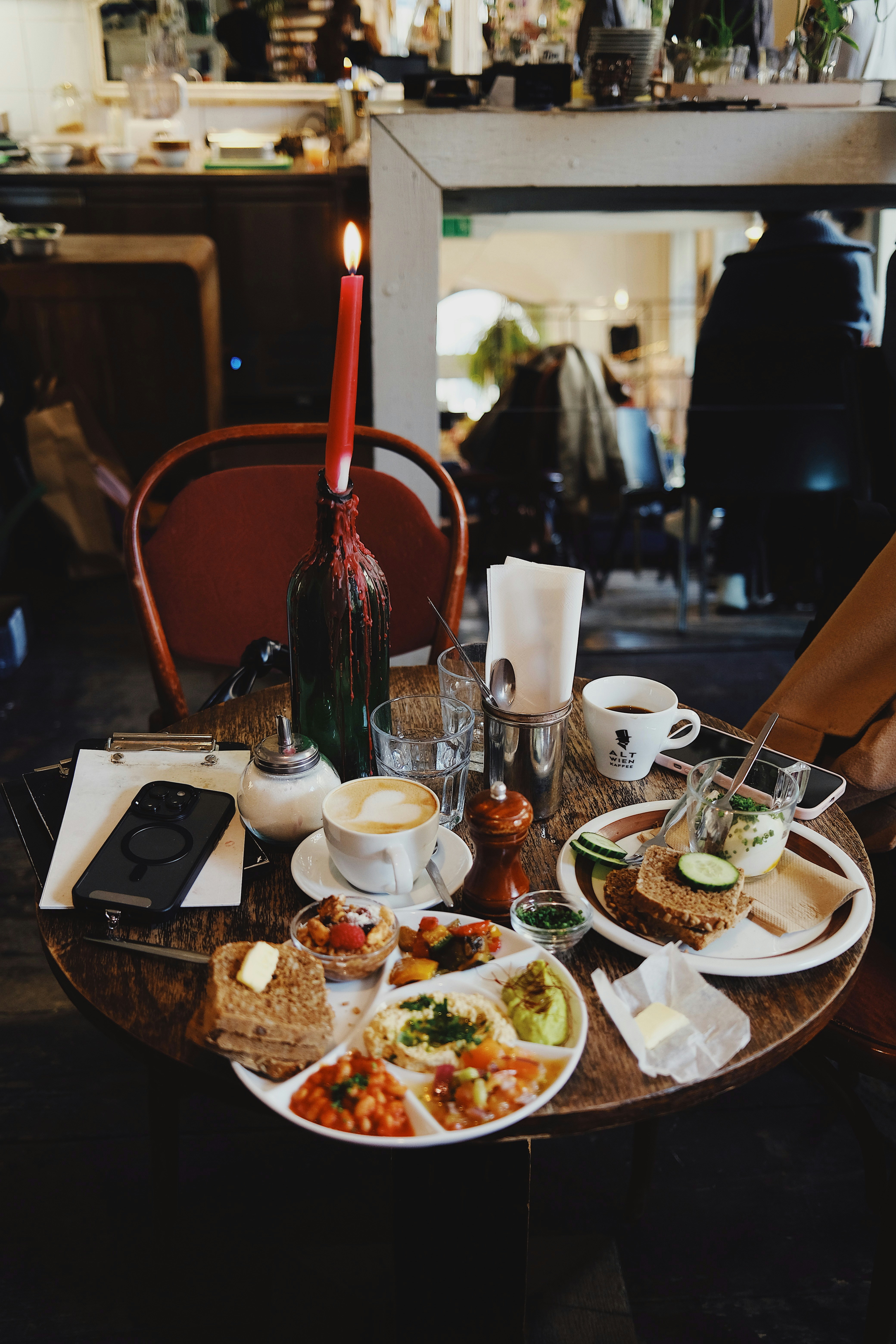 Table with breakfast spread and coffee, lit by candle.