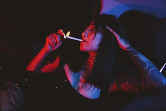 Woman lighting cigarette with red and blue lights