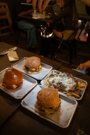 Three burgers and loaded fries on trays