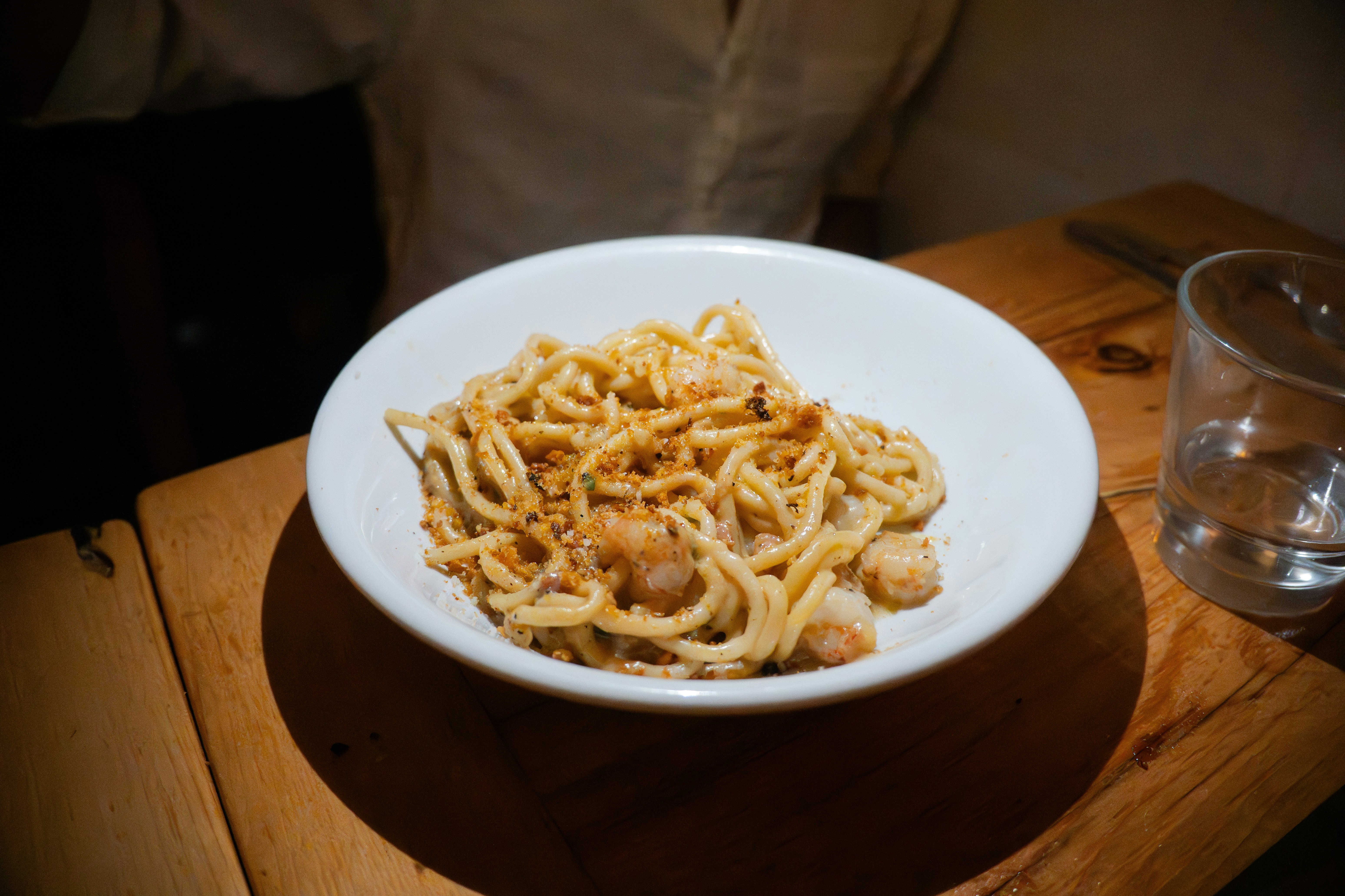 A bowl of pasta with seafood on a wooden table.