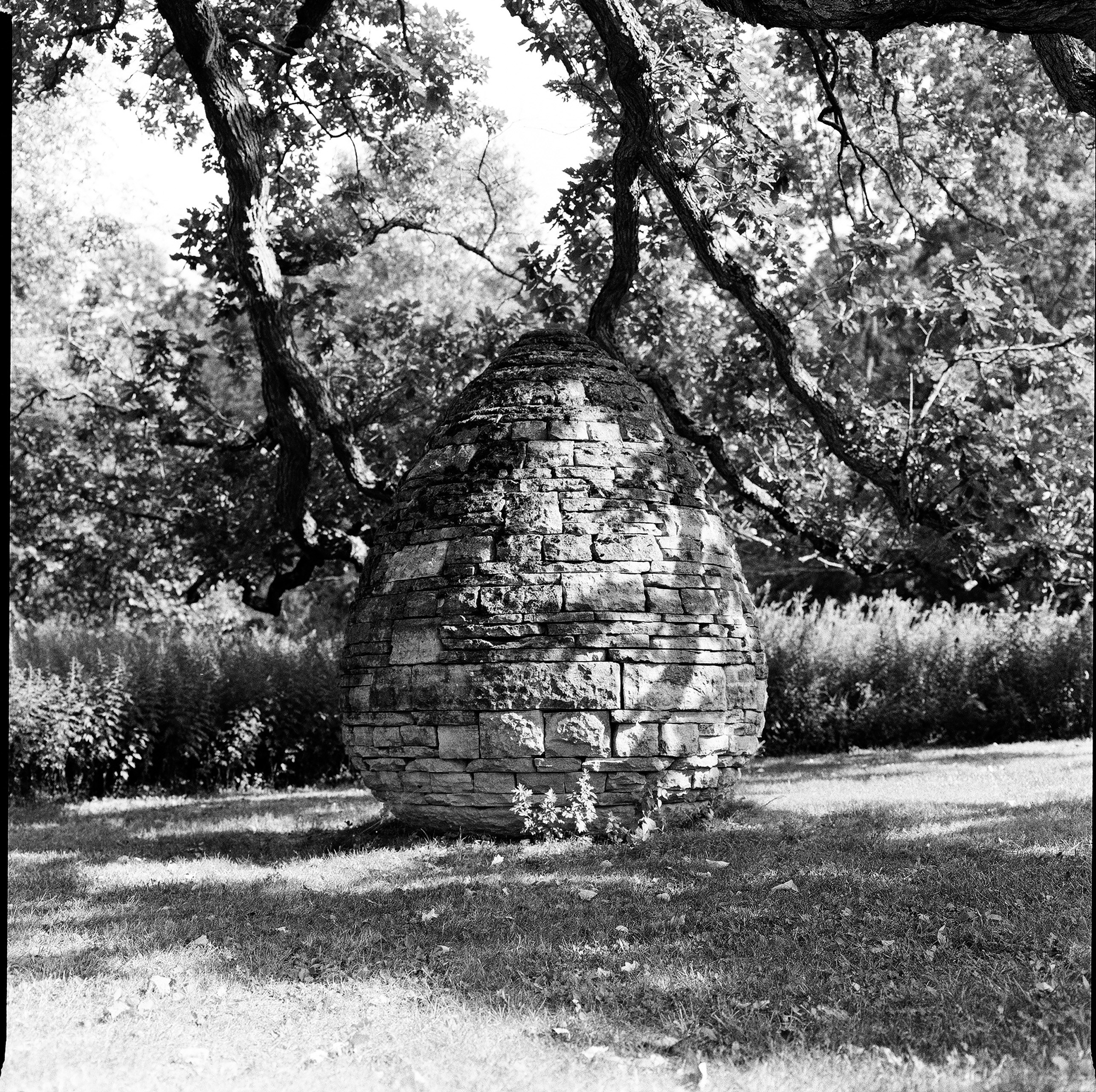 Steinstruktur, die an einen Bienenstock auf einer Rasenfläche erinnert.