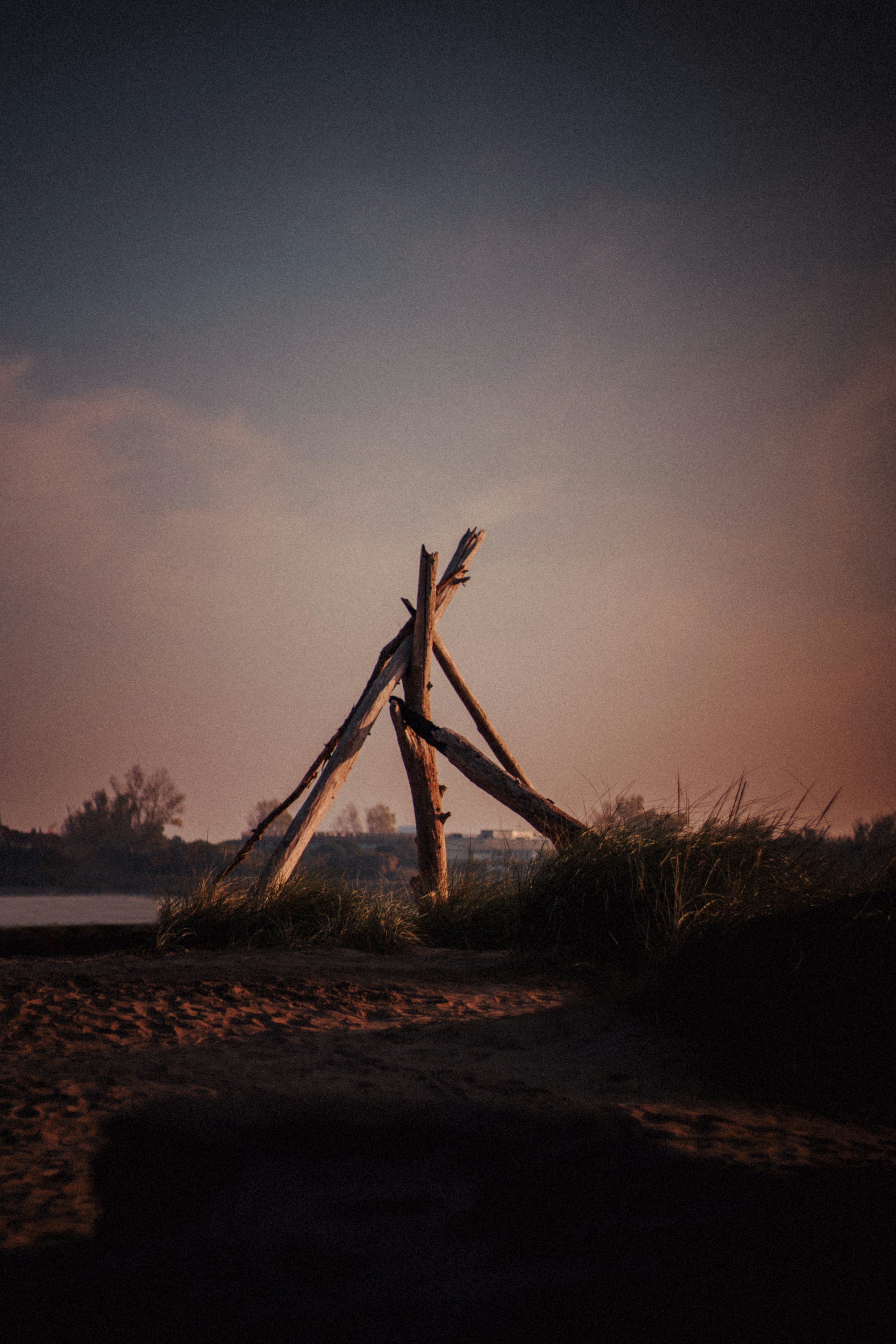 Driftwood structure on a sandy beach at dusk