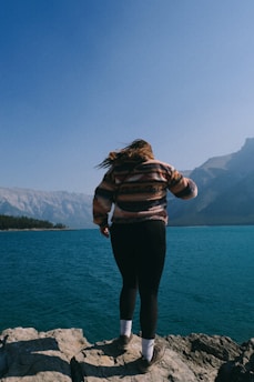 Woman standing on rocks overlooking a turquoise lake