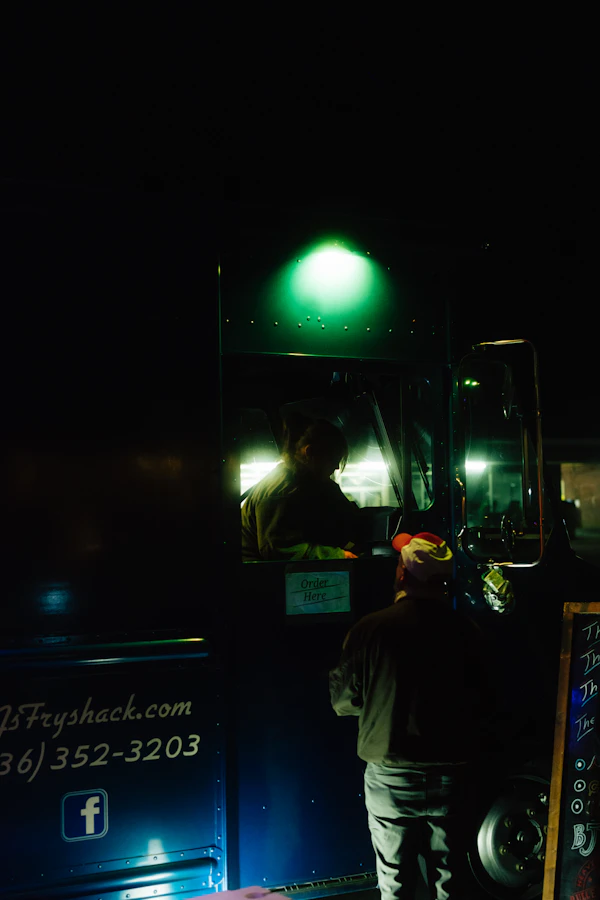 Goście zamawiający jedzenie przy food trucku wieczorem