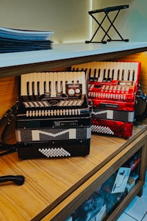 Two accordions displayed on a wooden shelf.