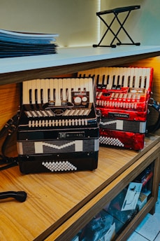 Two accordions displayed on a wooden shelf.