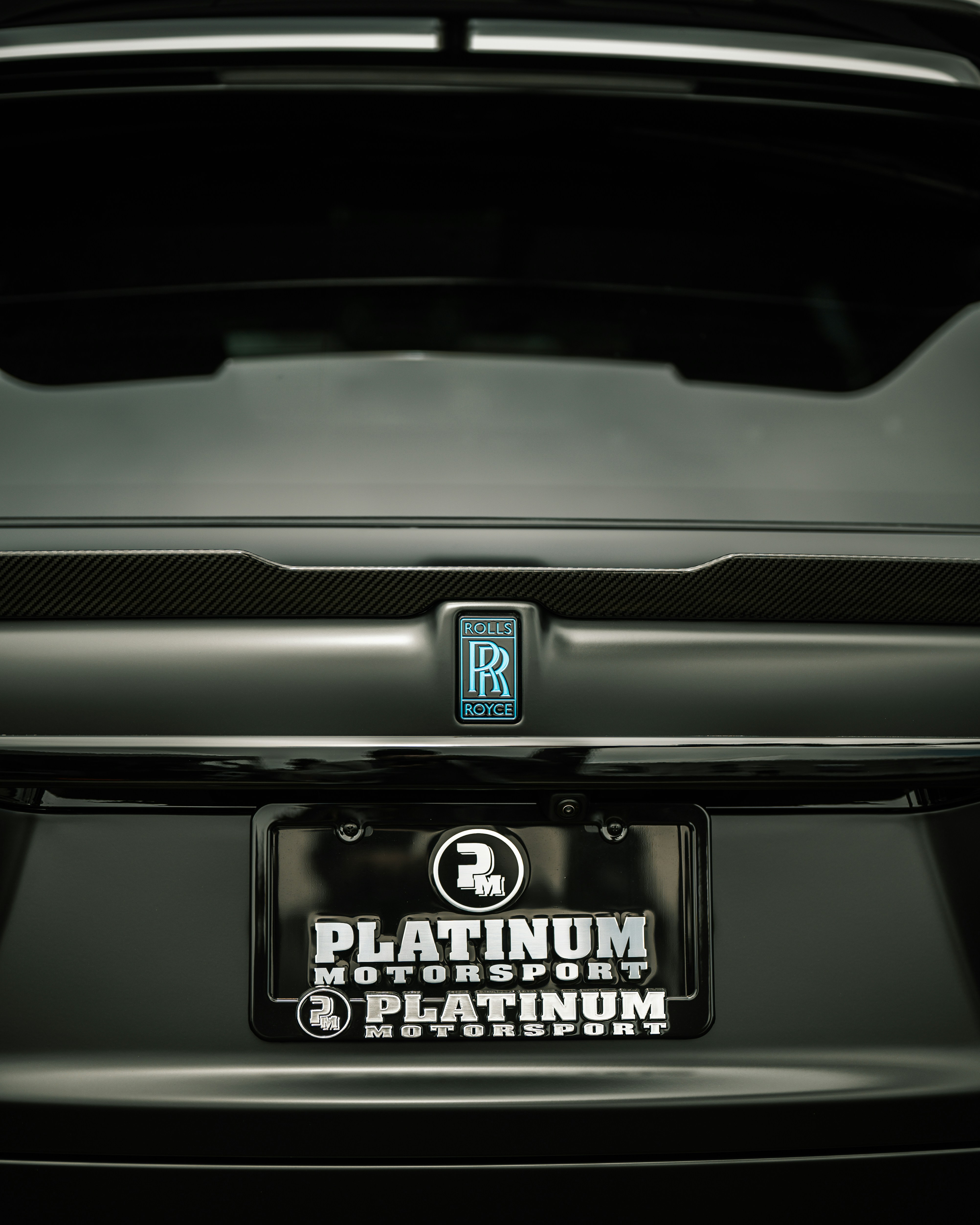 Close-up of a rolls-royce car's rear emblem and license plate.