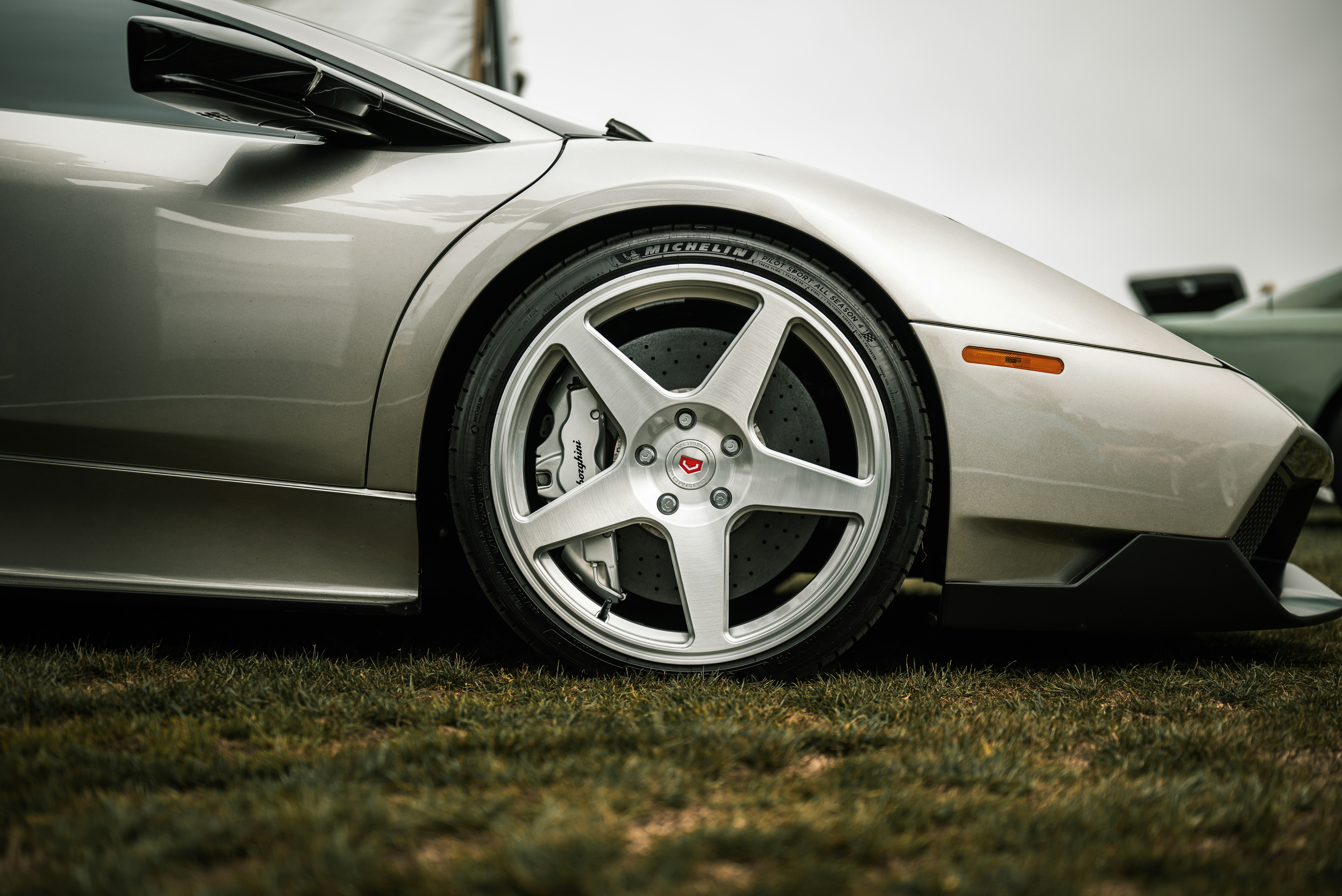 Close-up of a silver sports car wheel on grass