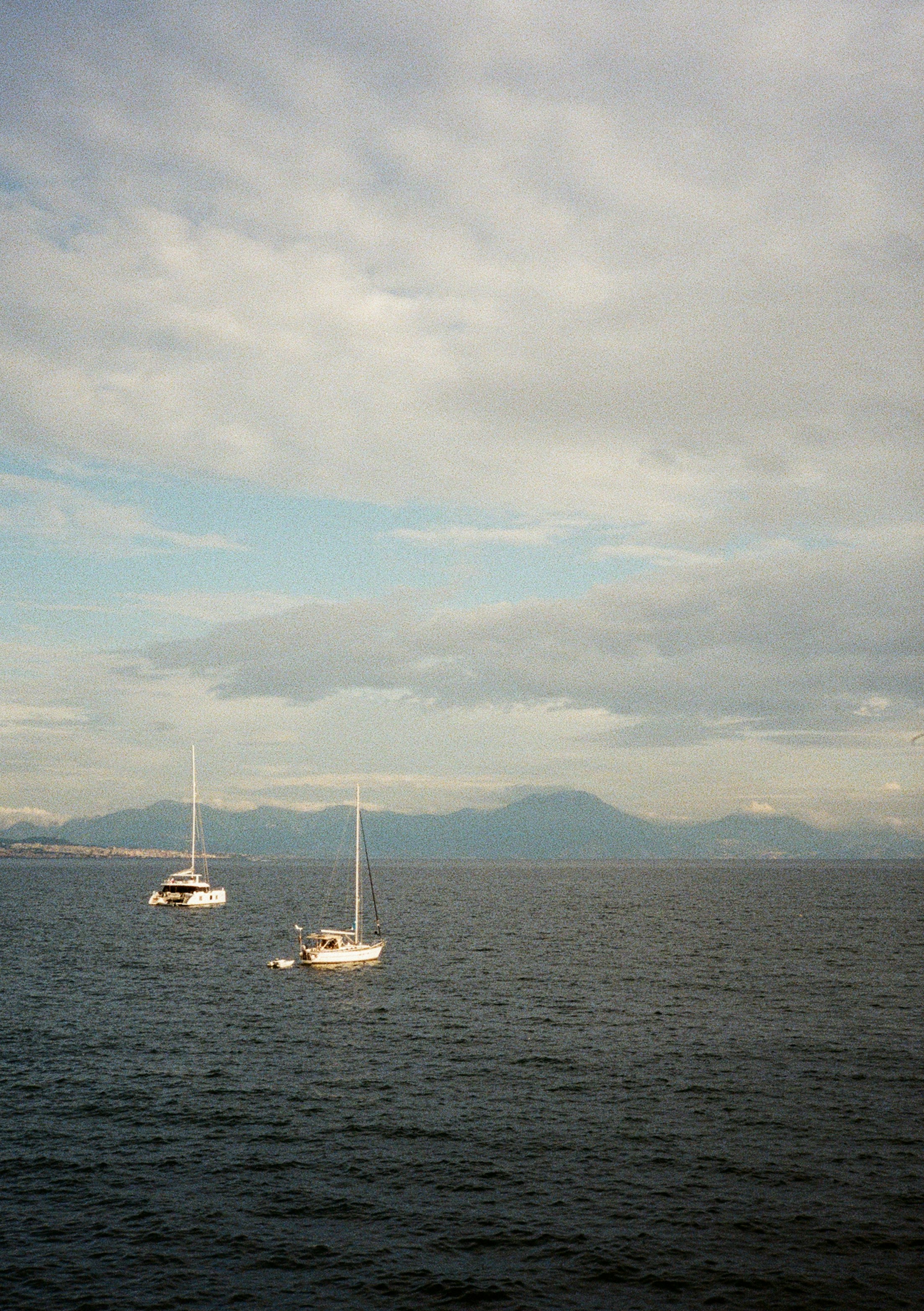 Two sailboats on the water with mountains beyond