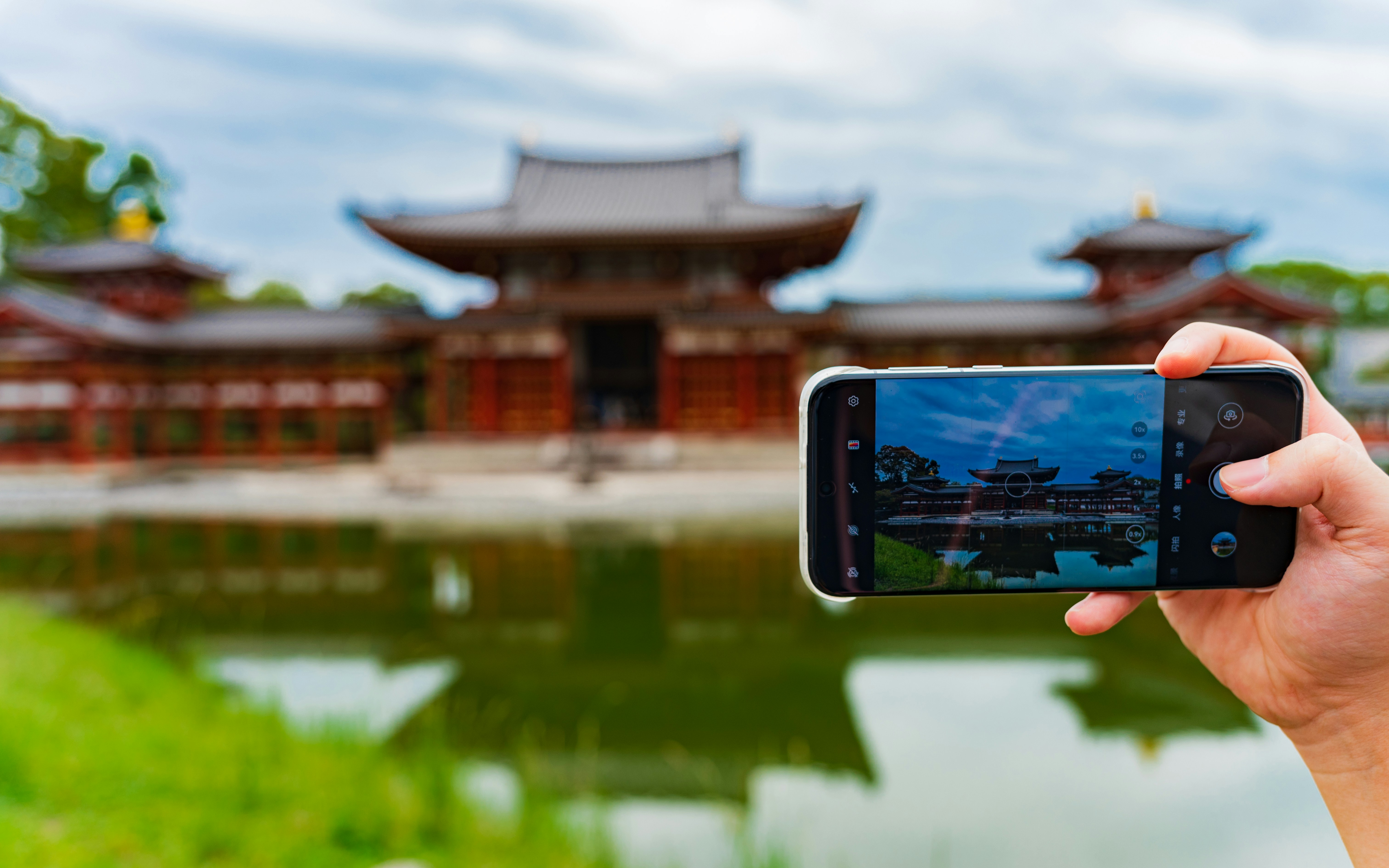 Person taking a picture of a temple with phone.